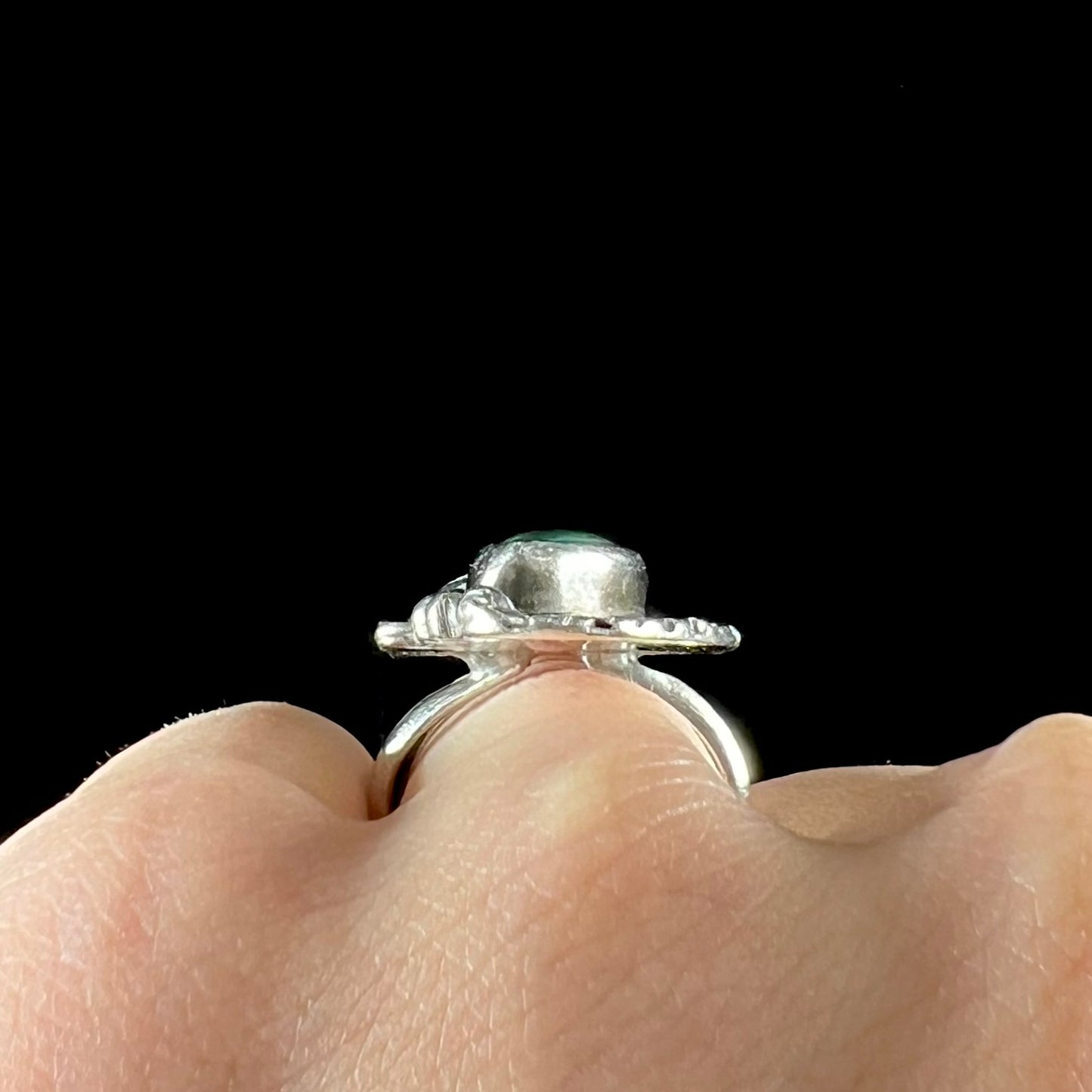 A sterling silver Navajo style ring set with a turquoise stone that shows colors of green, yellow, and reddish brown.