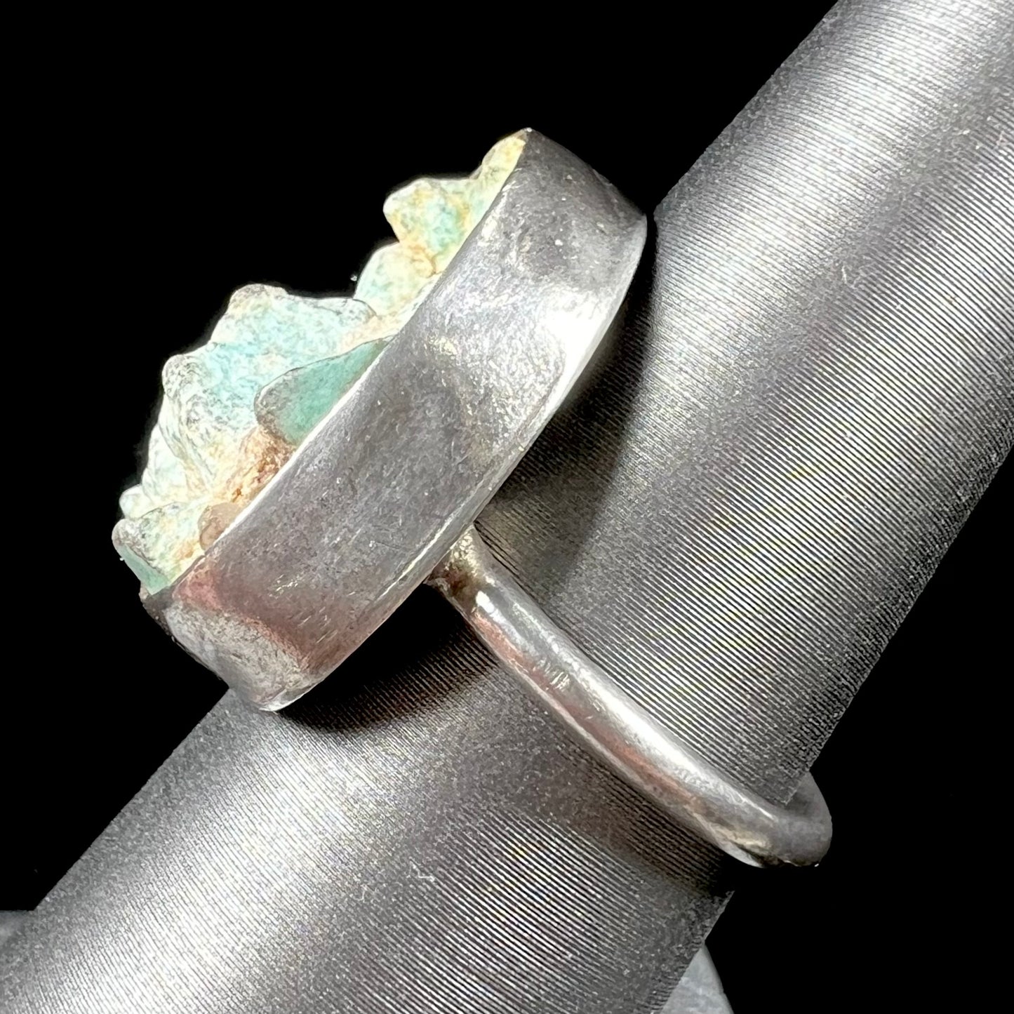 A handmade unisex sterling silver solitaire ring set with a rough, unpolished piece of turquoise stone.