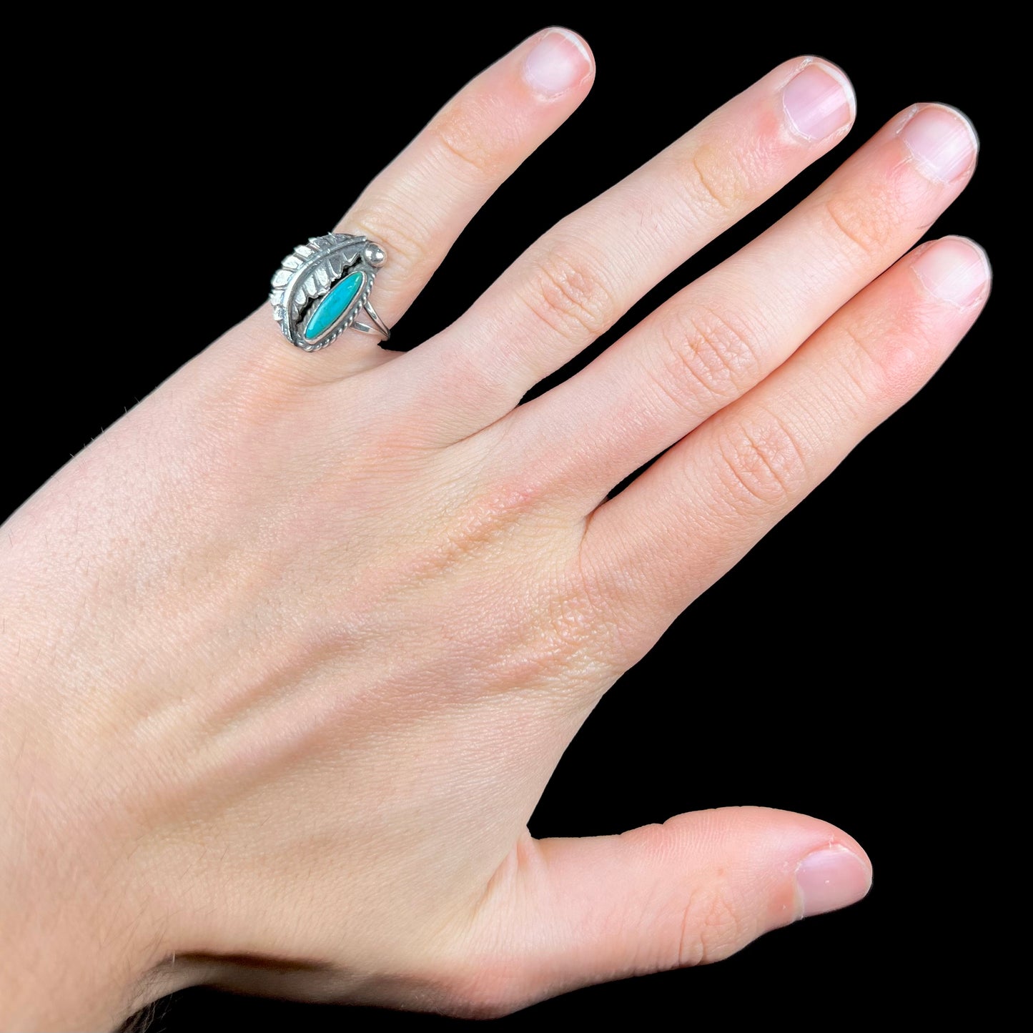 A ladies' sterling silver feather style ring set with a marquise cut turquoise stone.