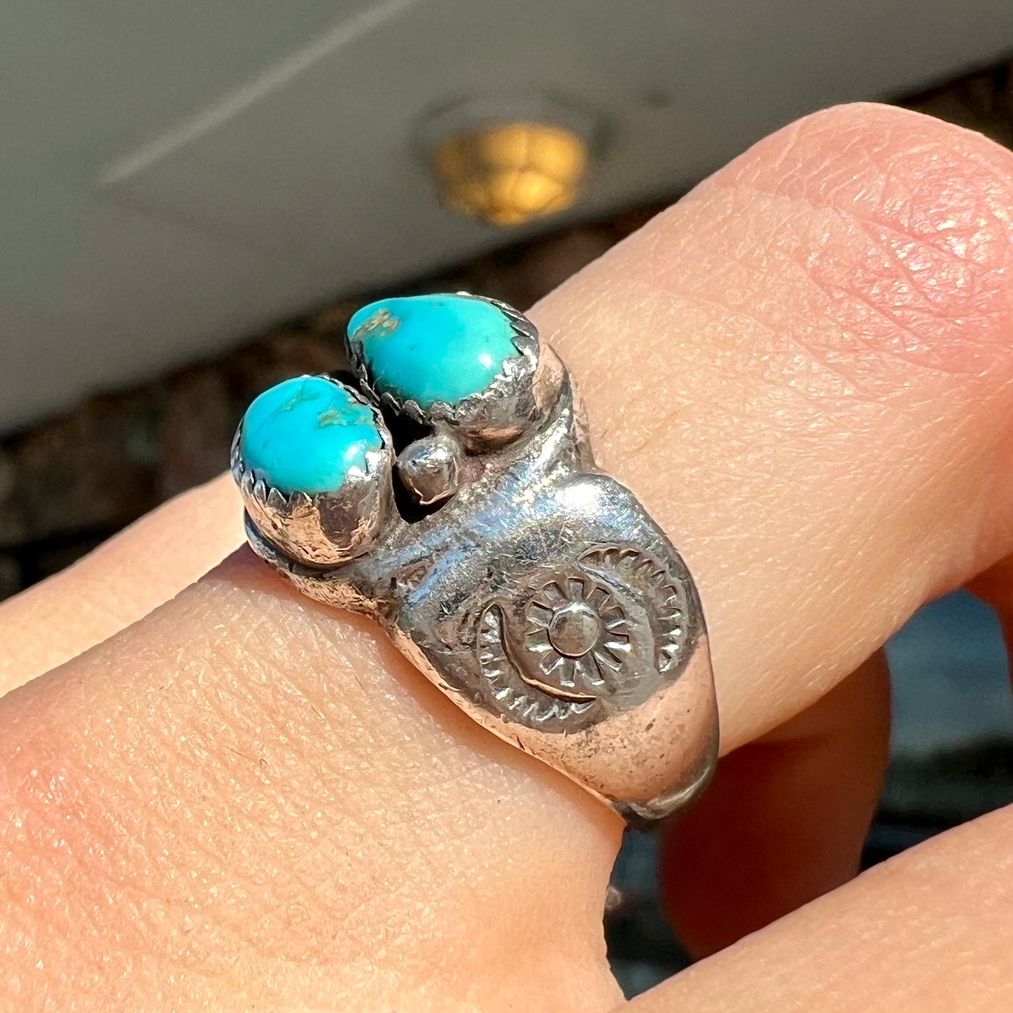 A unisex sterling silver ring bezel set with two Pilot Mountain turquoise stones.  The ring is stamped with sun patterns.