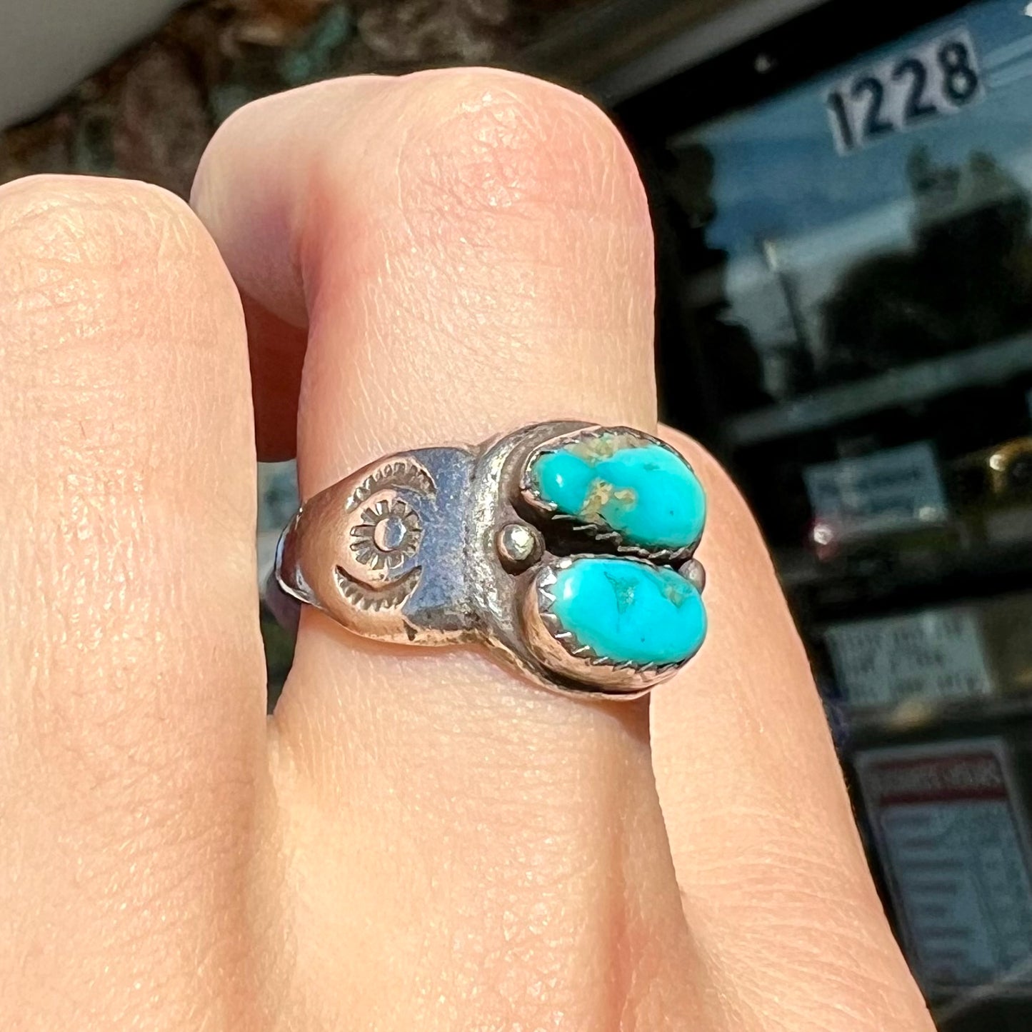 A unisex sterling silver ring bezel set with two Pilot Mountain turquoise stones.  The ring is stamped with sun patterns.