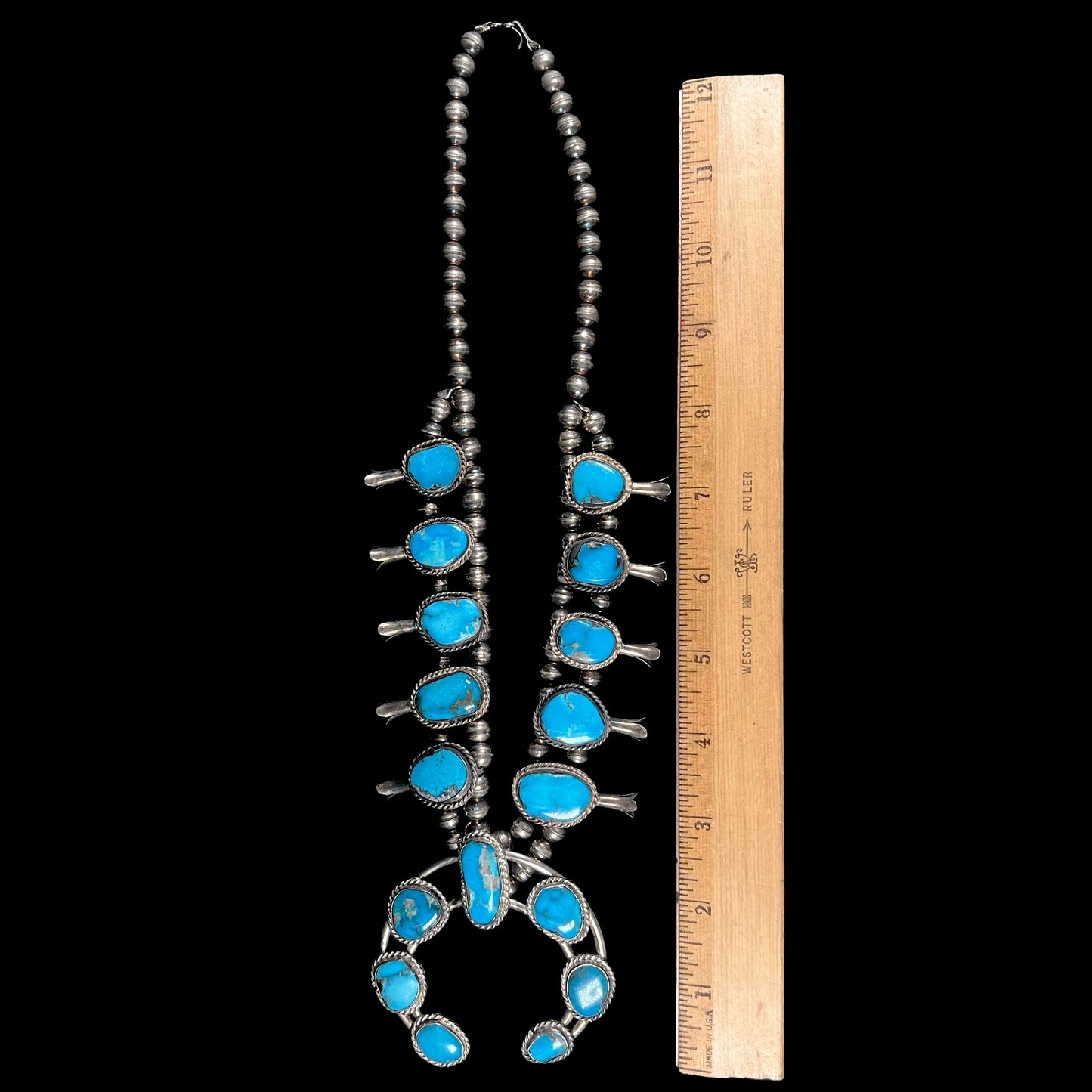 A vintage Navajo squash blossom necklace set with blue Kingman turquoise stones.