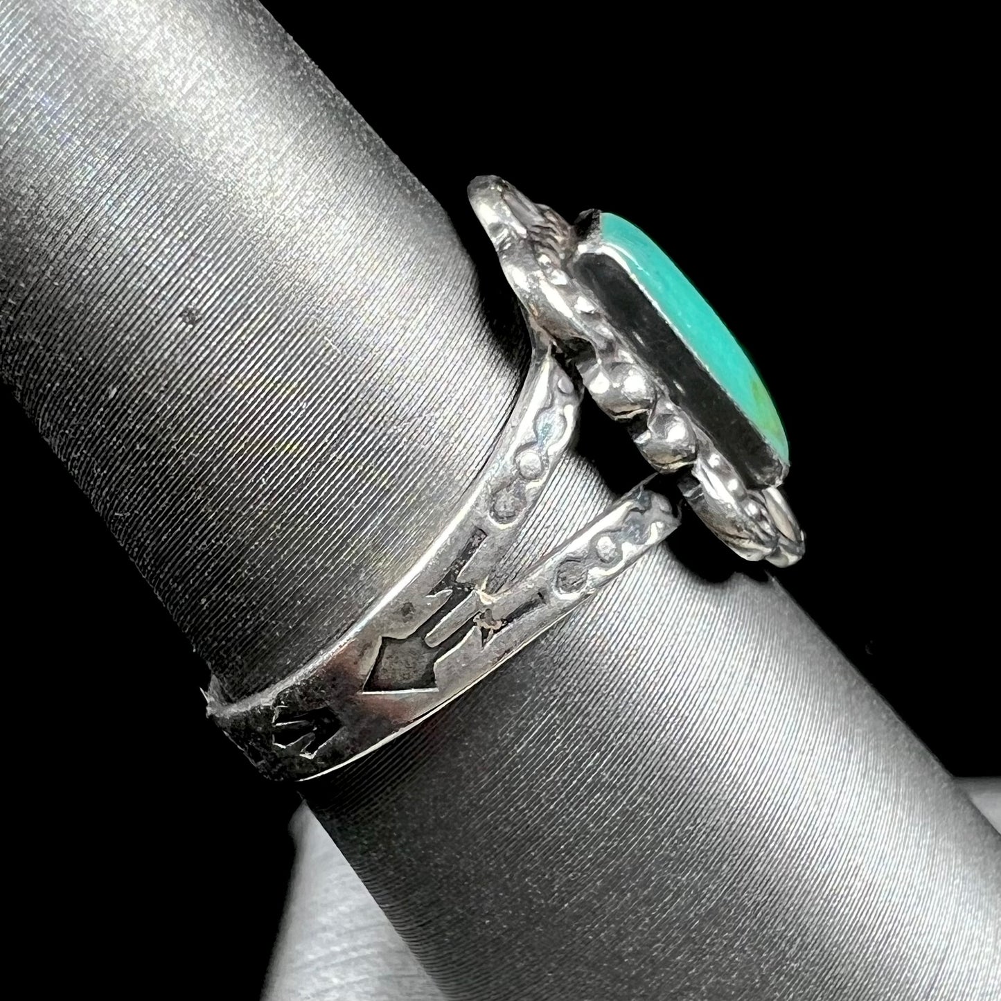 A ladies' silver ring stamped with Southwest style designs and set with a rectangular cabochon cut Royston turquoise stone.