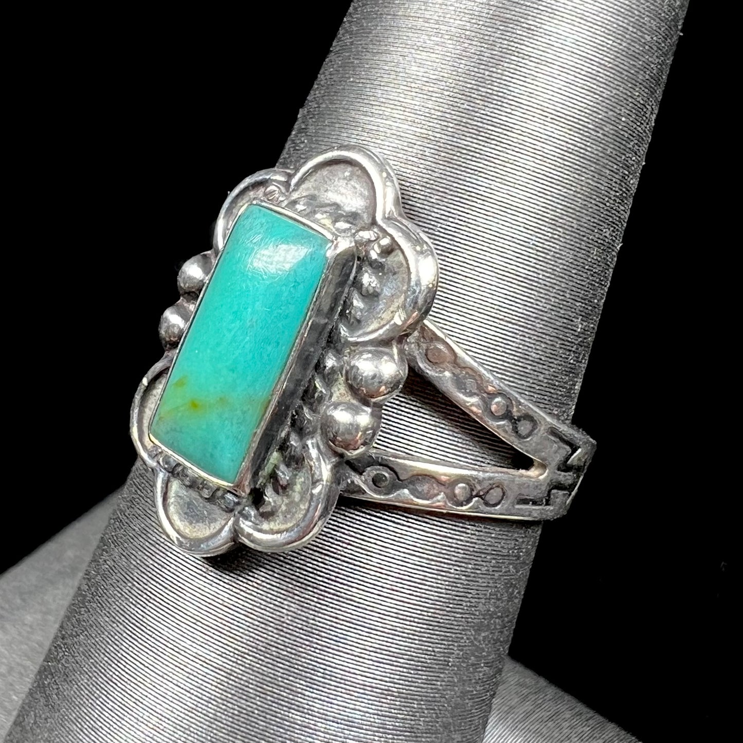 A ladies' silver ring stamped with Southwest style designs and set with a rectangular cabochon cut Royston turquoise stone.