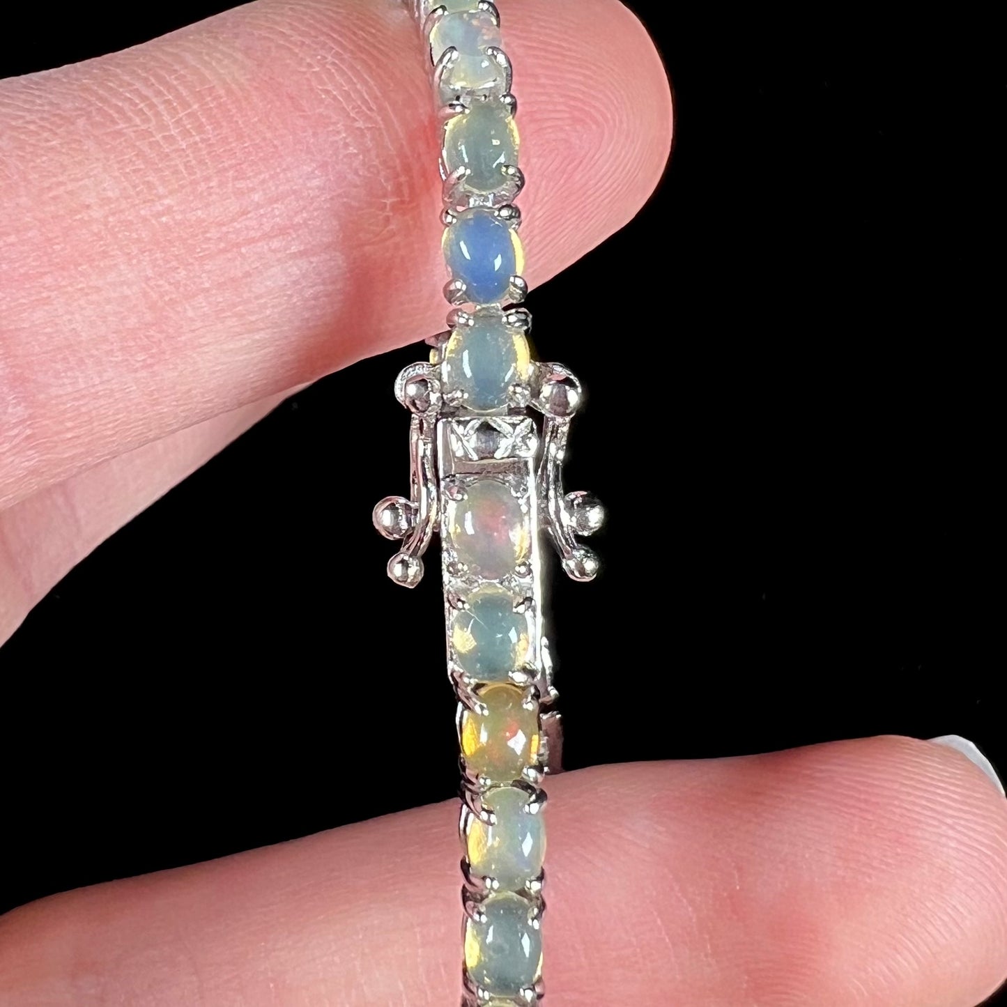 A ladies' sterling silver tennis style bracelet set with natural orange yellow Mexican fire opals.