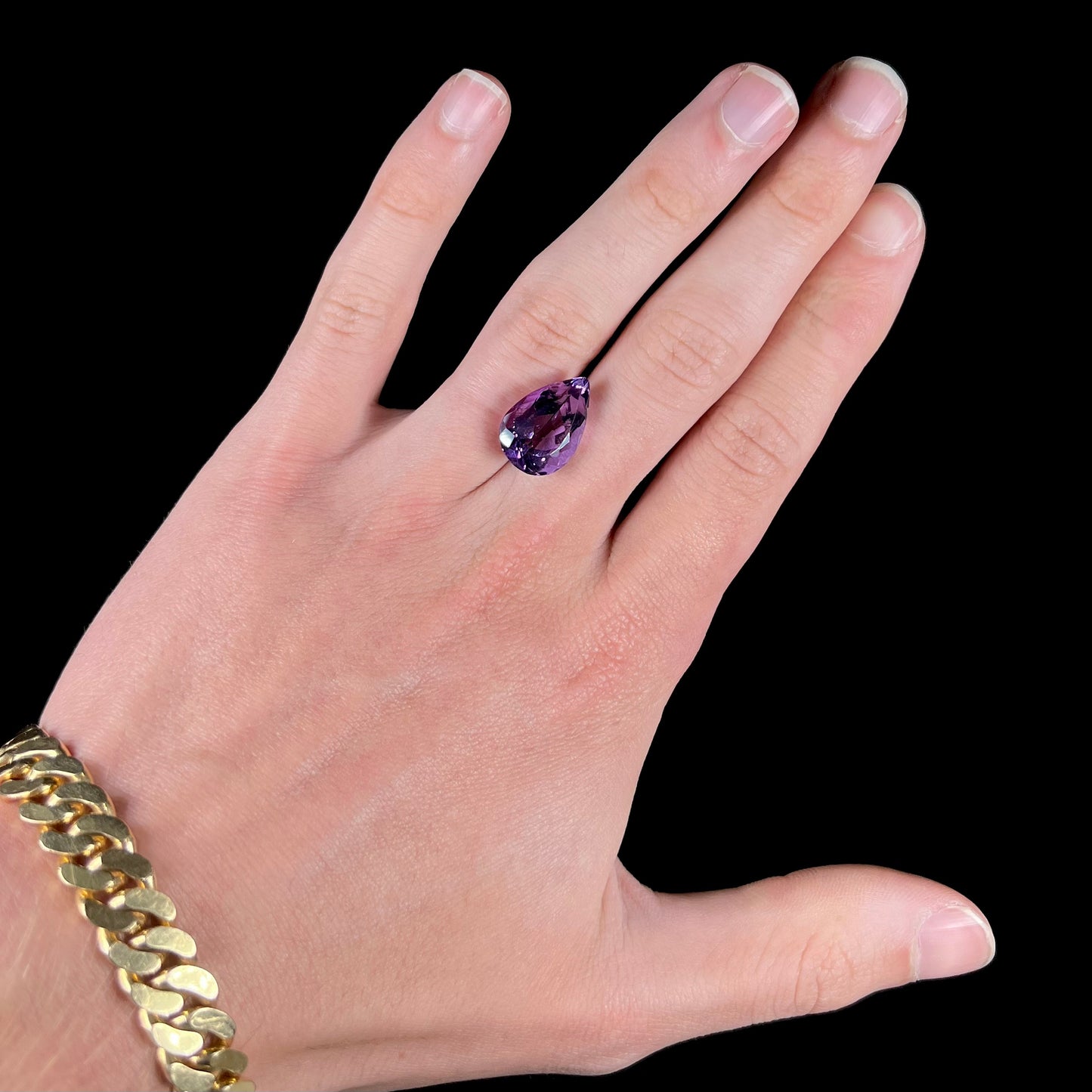 A loose, pear shaped amethyst gemstone. The stone is a medium purple color.
