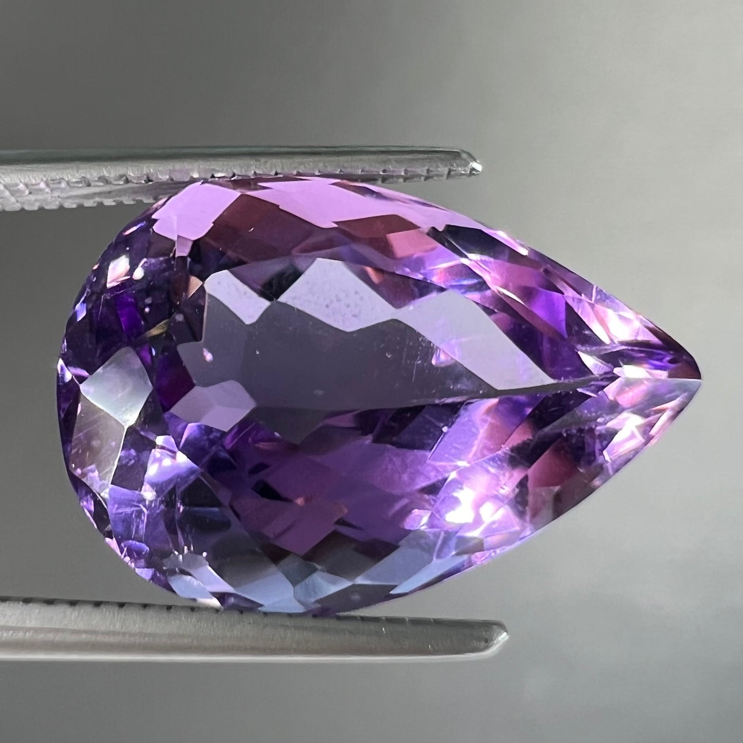 A loose, pear shaped amethyst gemstone. The stone is a medium purple color.