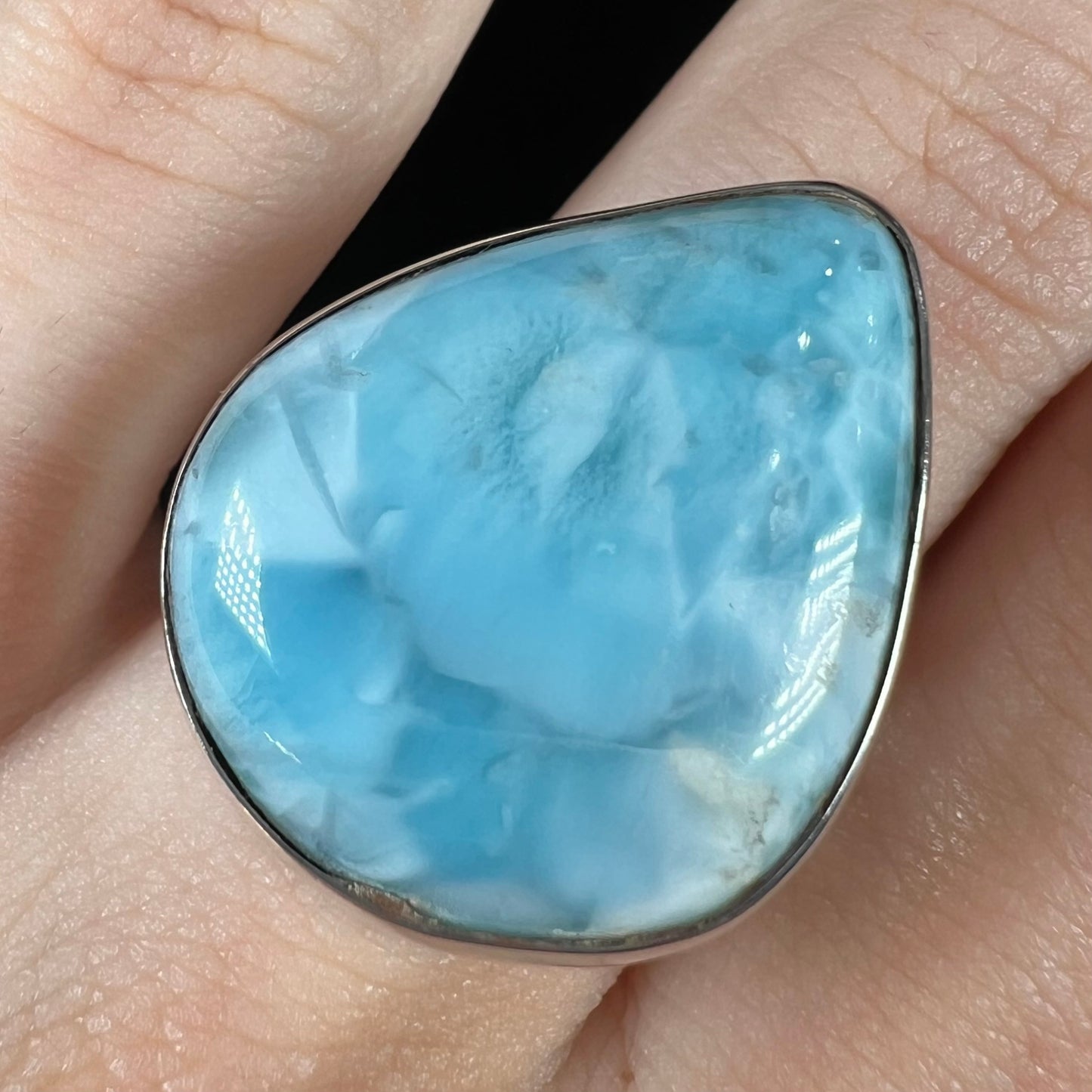 A ladies' large, pear shaped larimar solitaire ring in sterling silver. The larimar stone measures an inch long.