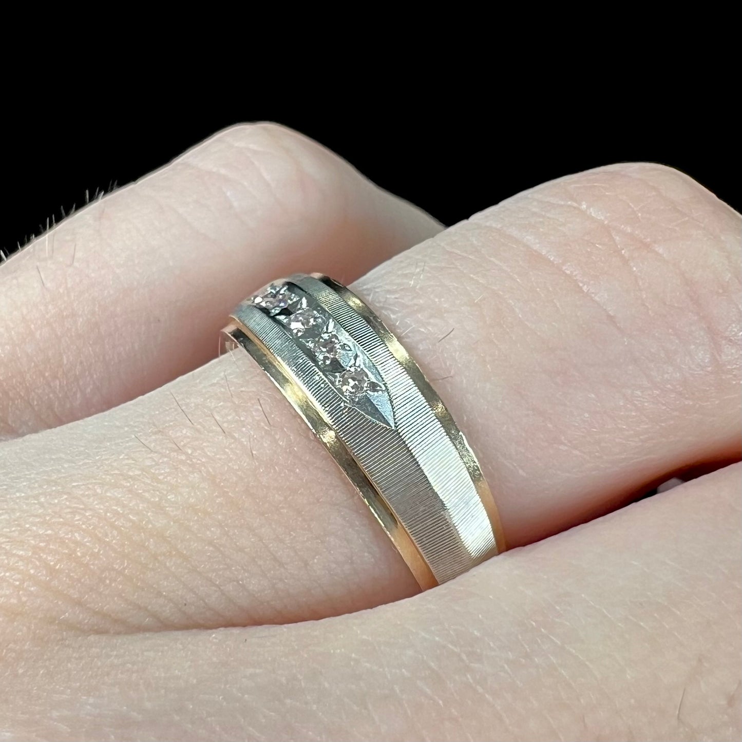 A unisex, two-tone white and yellow gold diamond wedding band. The white gold is textured.