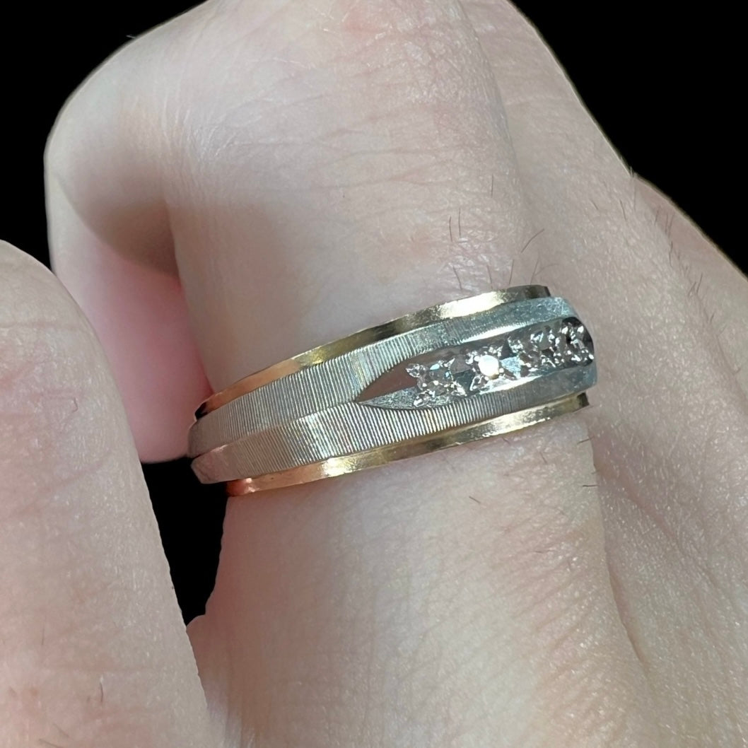 A unisex, two-tone white and yellow gold diamond wedding band. The white gold is textured.