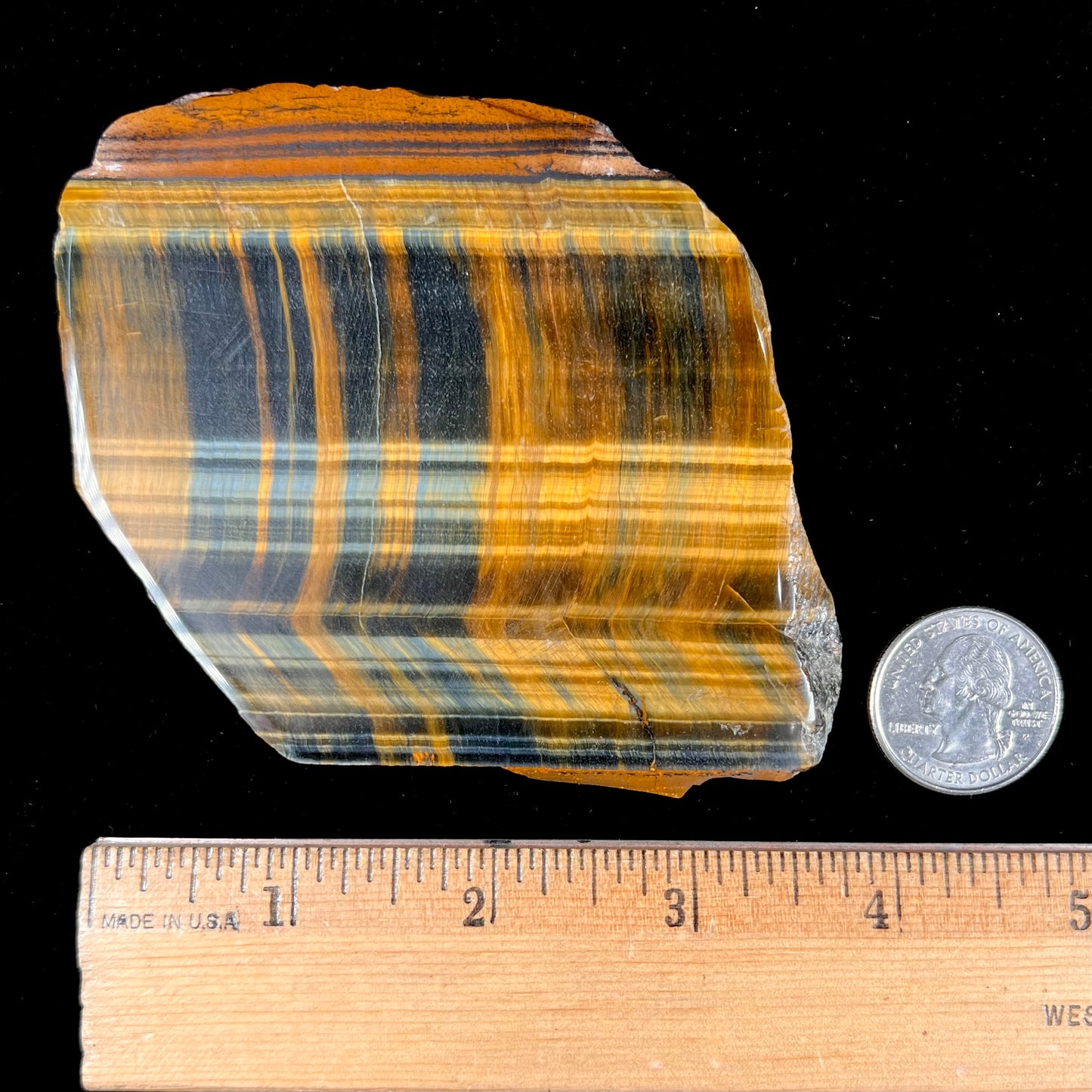 A polished slab of yellow tiger's eye with blue streaks.
