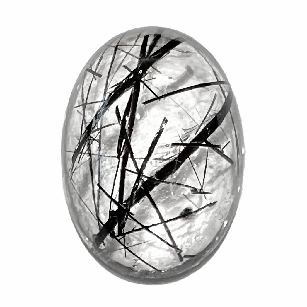 A loose, oval cabochon cut clear quartz stone with black tourmaline needle inclusions. The gemstone weighs 13.05 carats.