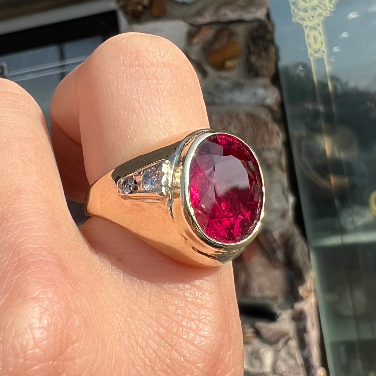 A men's yellow gold ring set with an oval cut rubellite tourmaline with diamond accents.