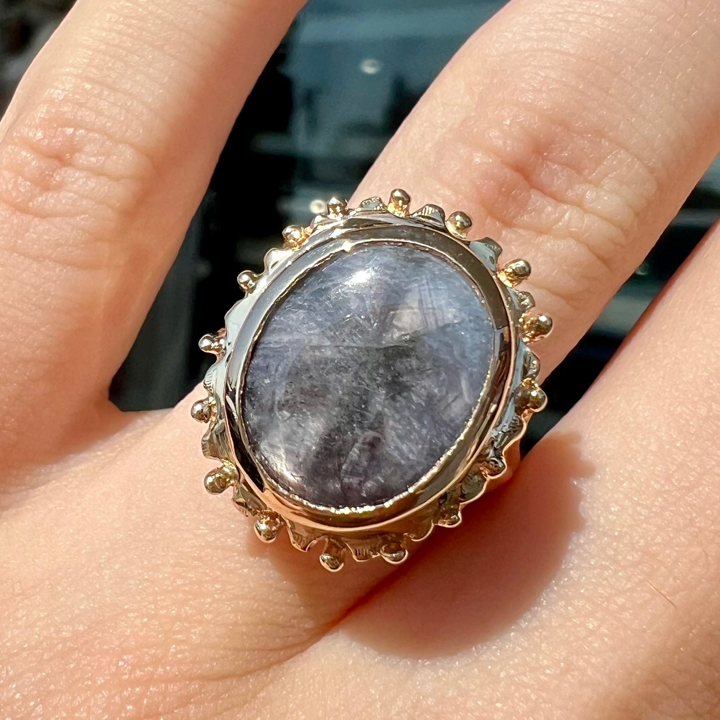 A ladies' yellow gold solitaire ring mounted with a gray trapiche star sapphire.