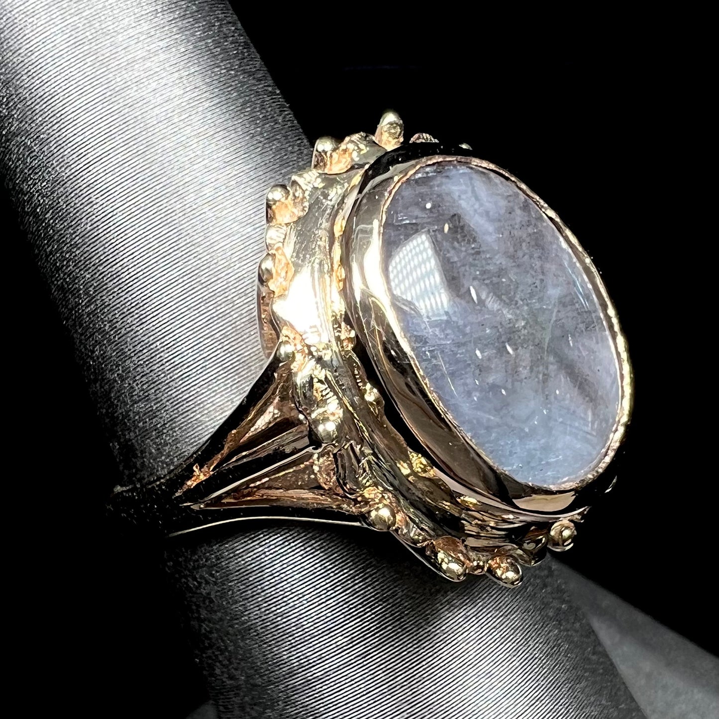 A ladies' yellow gold solitaire ring mounted with a gray trapiche star sapphire.