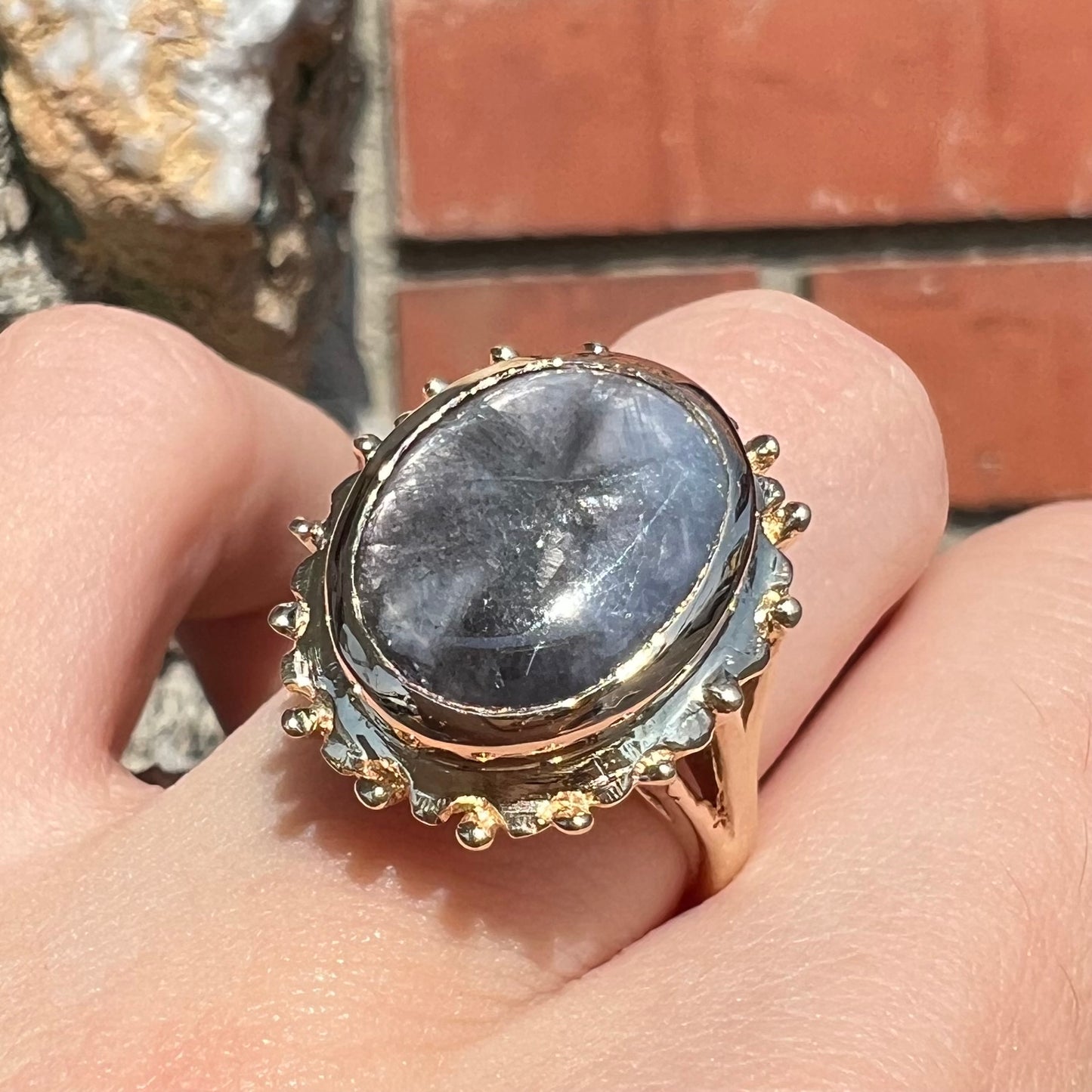 A ladies' yellow gold solitaire ring mounted with a gray trapiche star sapphire.
