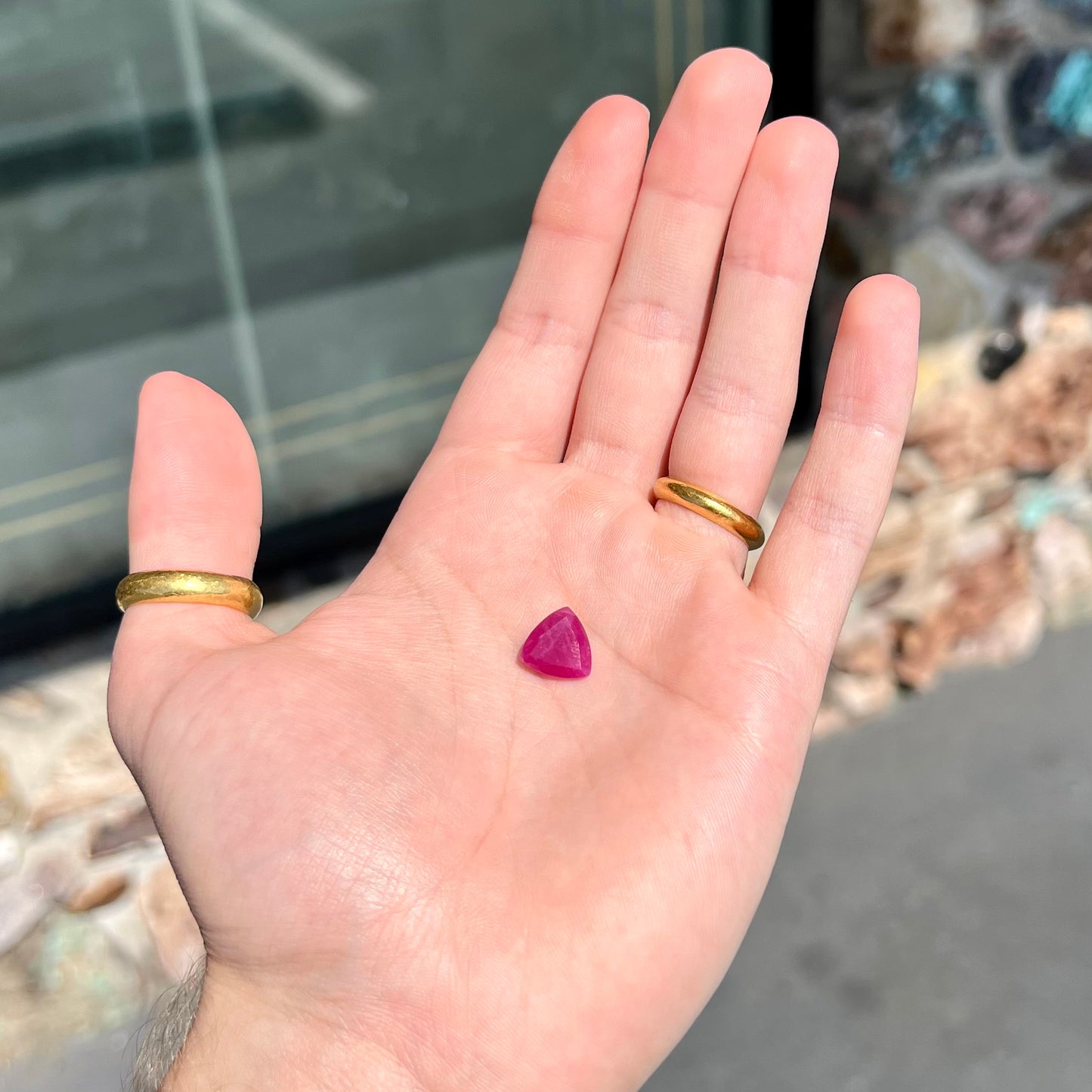 A loose, faceted trillion cut, natural, commercial grade ruby gemstone. The stone is purplish red color.