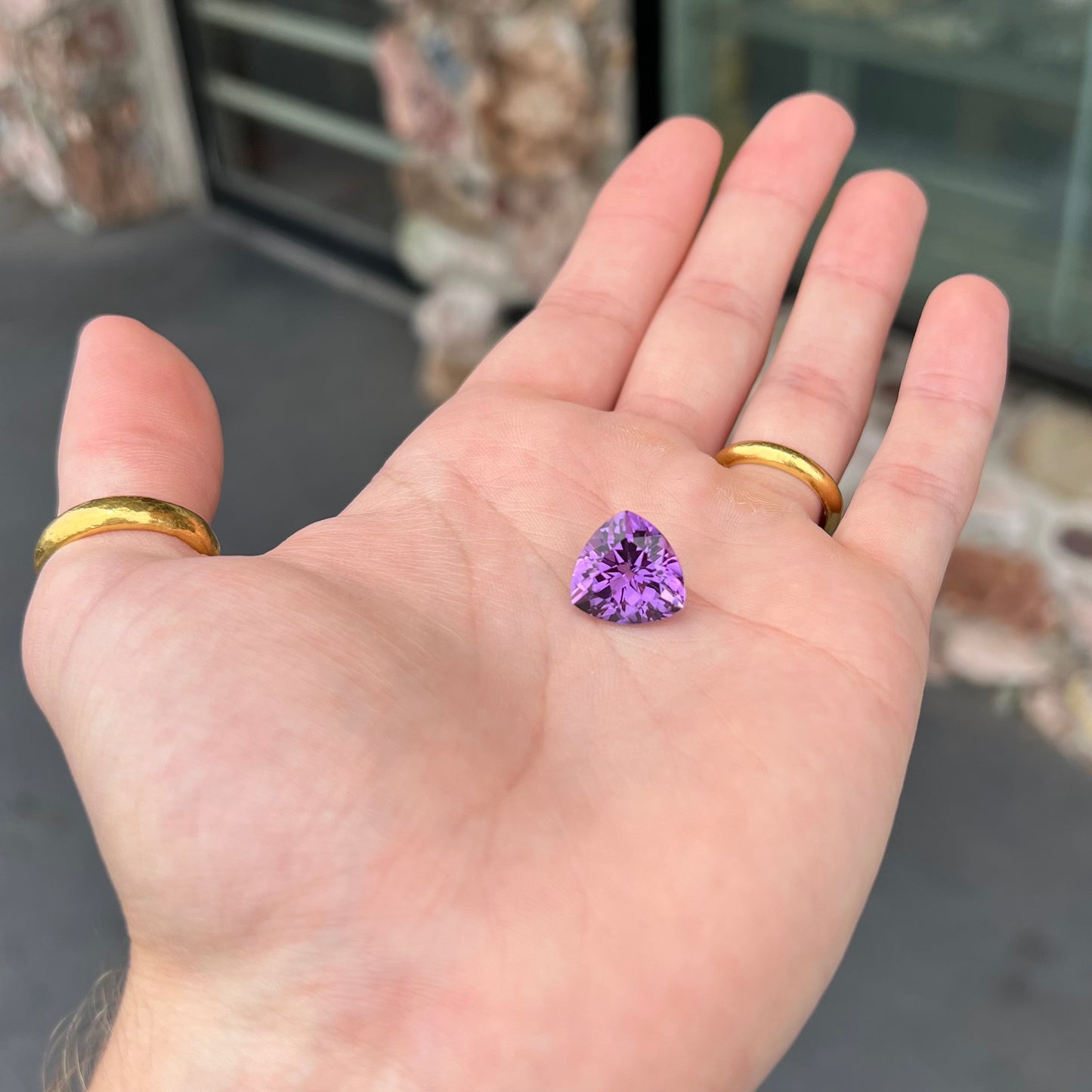 A loose, faceted trillion cut amethyst gemstone.