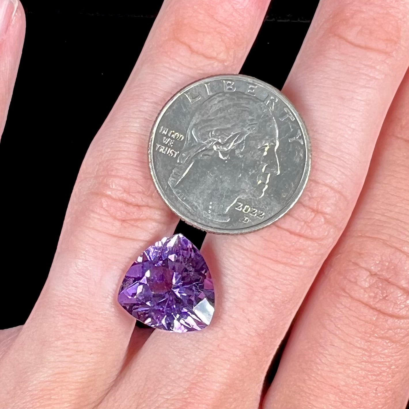 A loose, faceted trillion cut amethyst gemstone.