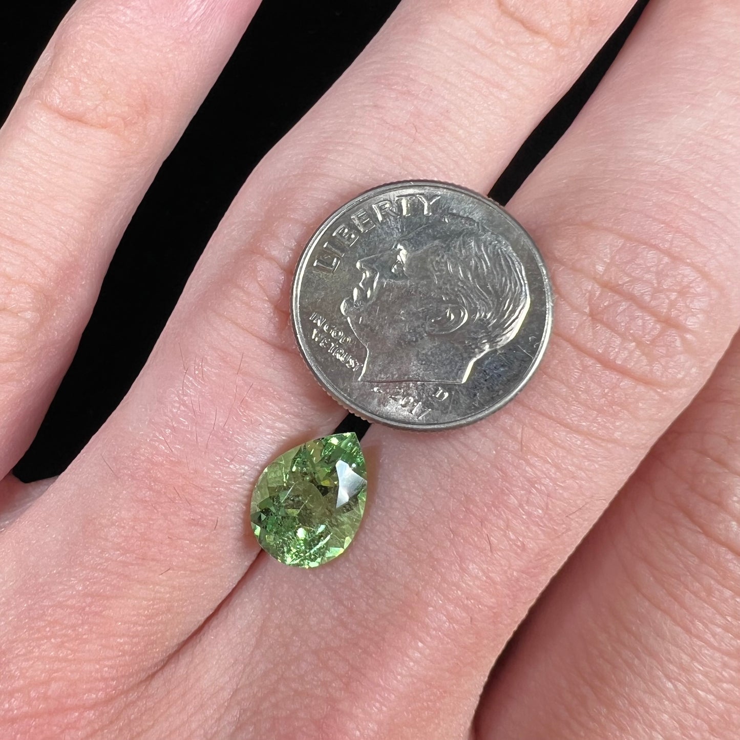 A loose, pear shaped tsavorite garnet gemstone. The stone is yellowish green.
