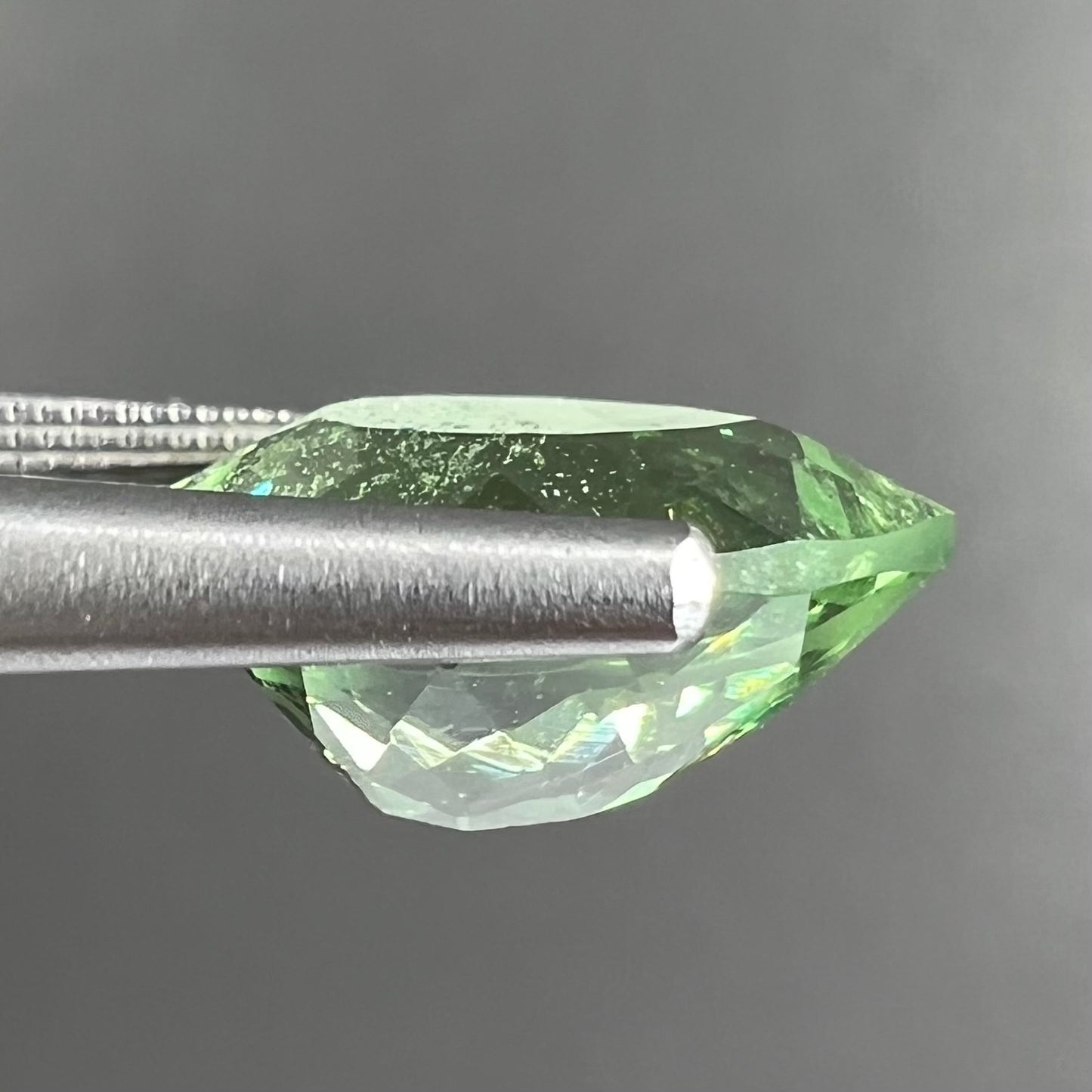 A loose, pear shaped tsavorite garnet gemstone. The stone is yellowish green.