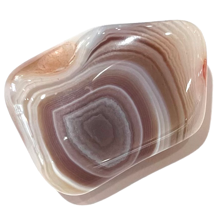 A tumbled banded agate stone.  The pattern of the stone resembles a banded puddle.