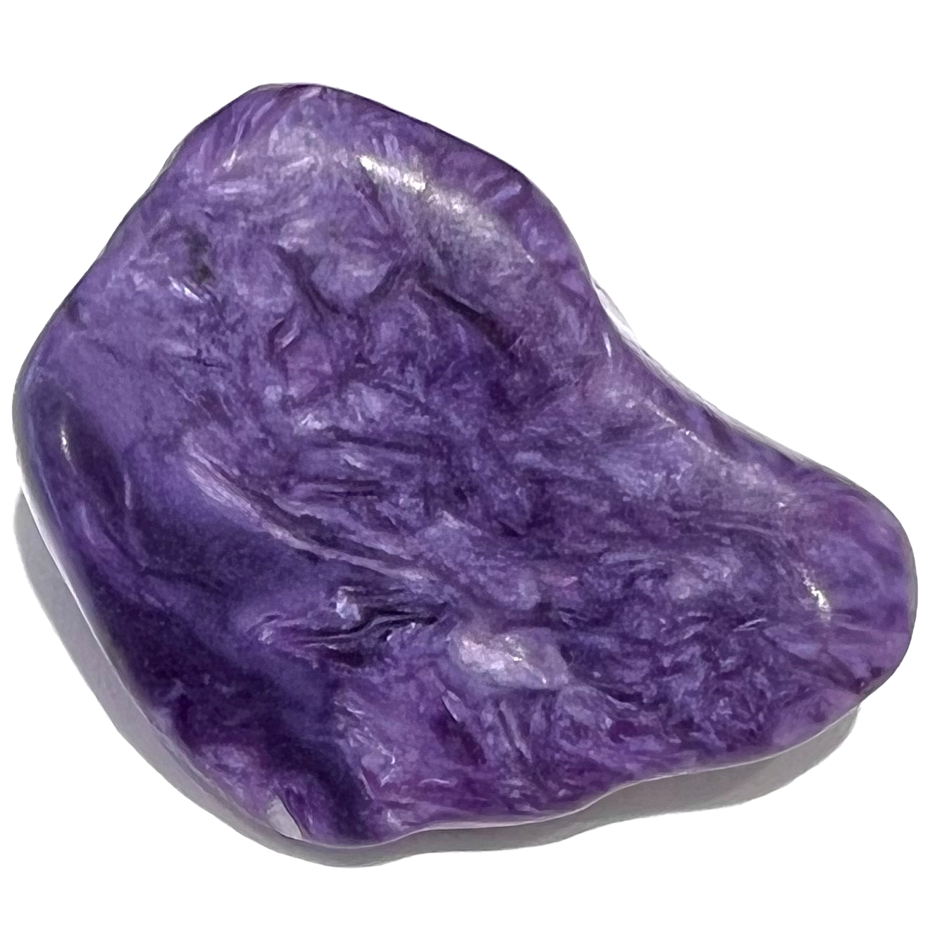 A tumble polished charoite stone.  The material is naturally stained purple, white, and black.
