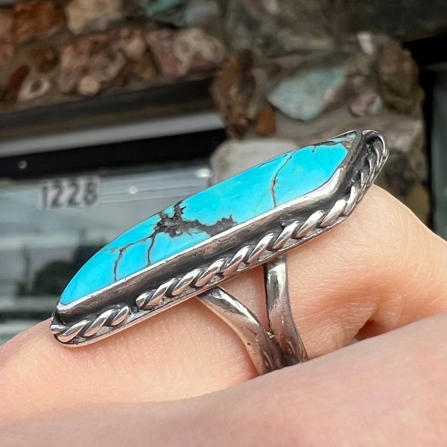 A vintage, Southwest style sterling silver ring set with a natural turquoise stone. The stone is blue with a black matrix.