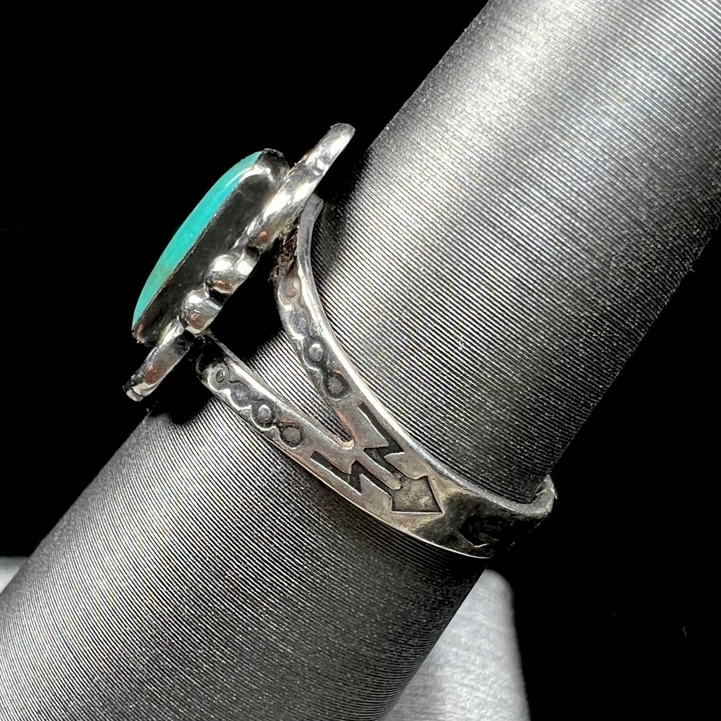 A ladies' silver ring stamped with Southwest style designs and set with a rectangular cabochon cut Royston turquoise stone.