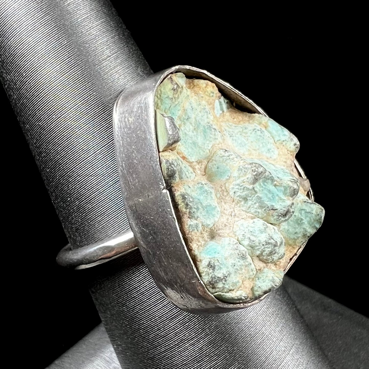 A handmade unisex sterling silver solitaire ring set with a rough, unpolished piece of turquoise stone.