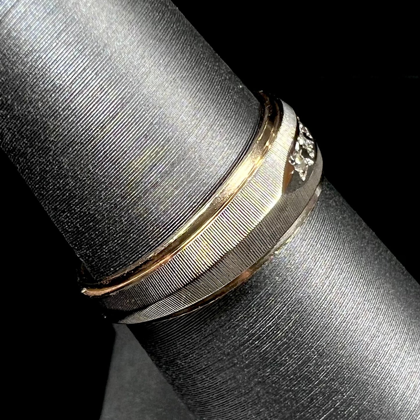 A unisex, two-tone white and yellow gold diamond wedding band. The white gold is textured.