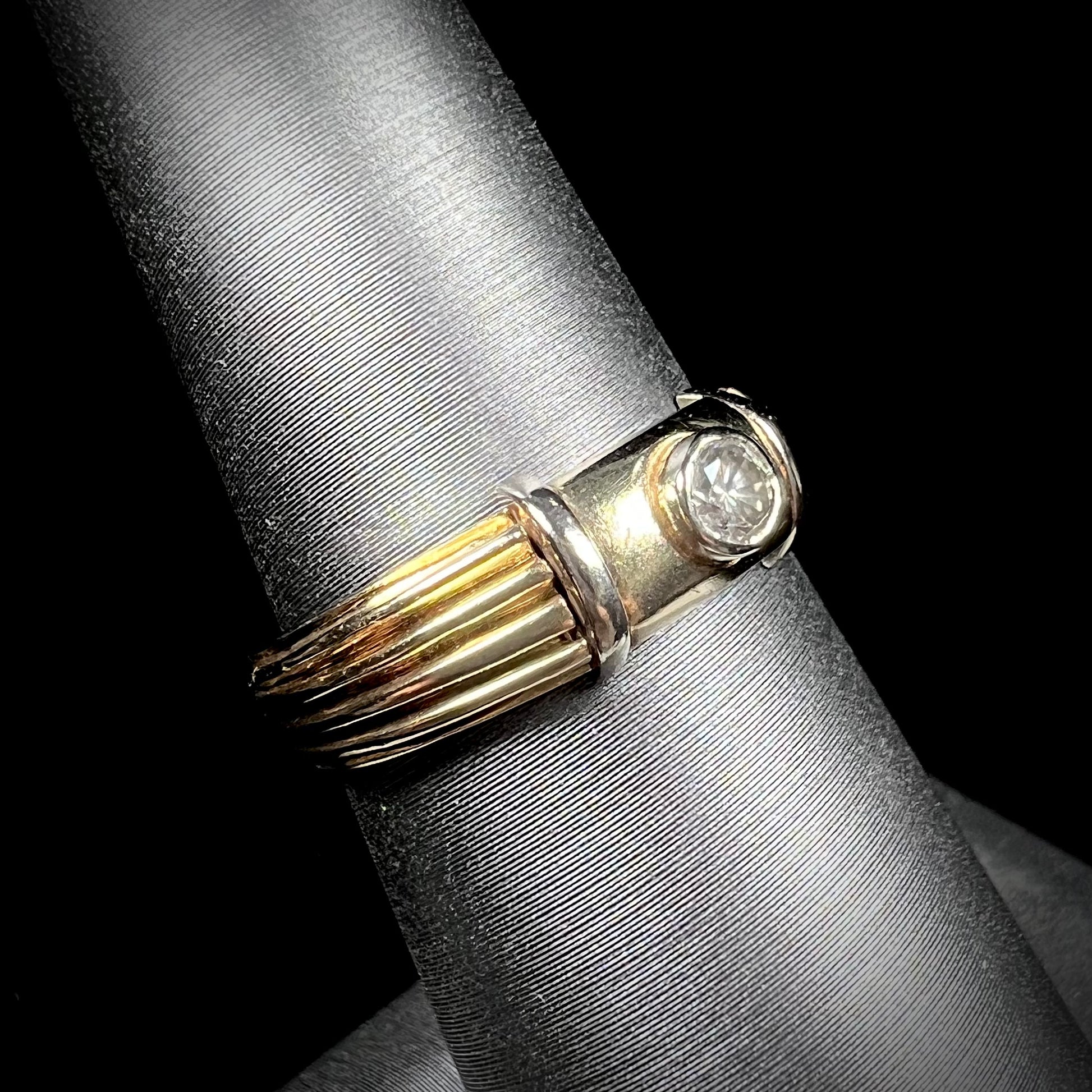 A unisex, vintage style two tone yellow and white gold wedding ring bezel set with a round diamond.