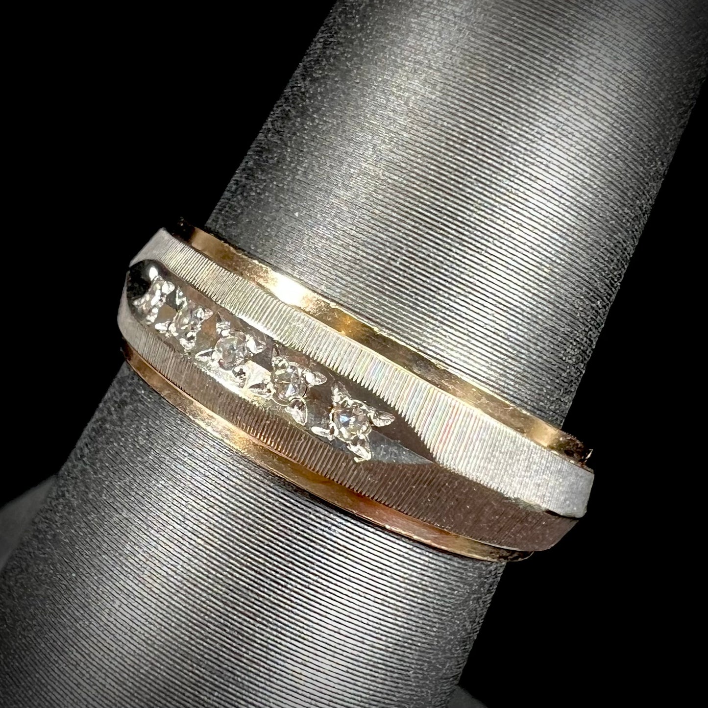 A unisex, two-tone white and yellow gold diamond wedding band. The white gold is textured.