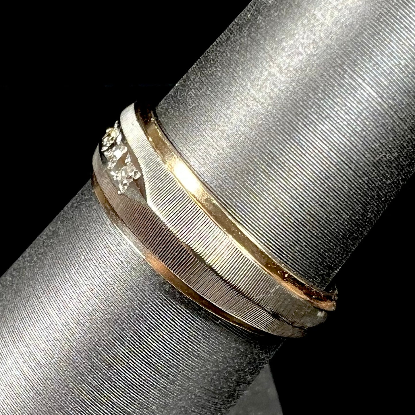 A unisex, two-tone white and yellow gold diamond wedding band. The white gold is textured.