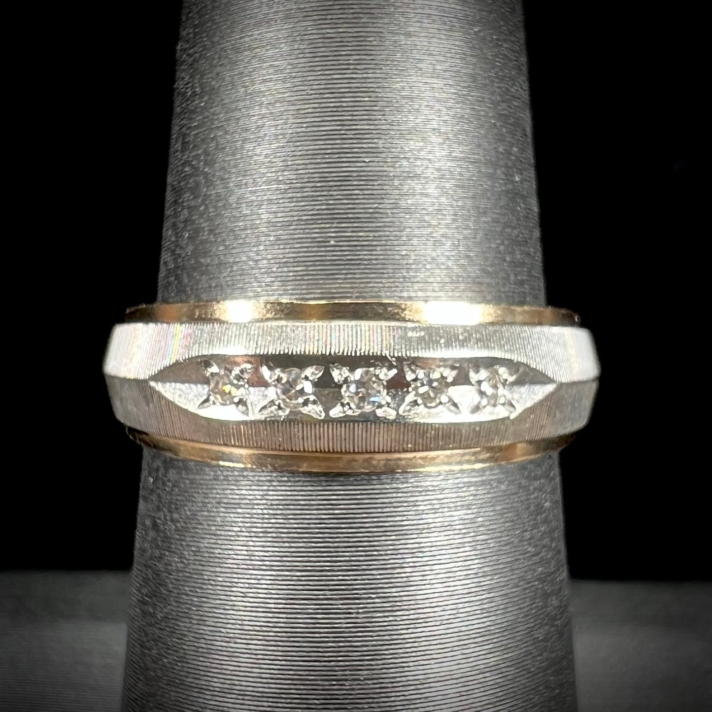 A unisex, two-tone white and yellow gold diamond wedding band. The white gold is textured.