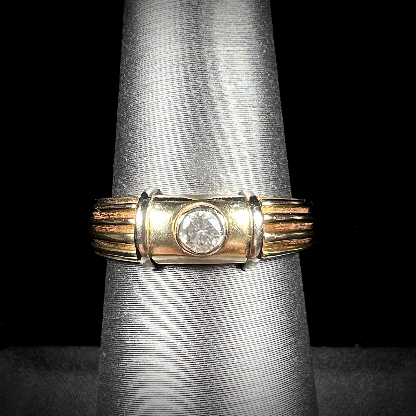 A unisex, vintage style two tone yellow and white gold wedding ring bezel set with a round diamond.