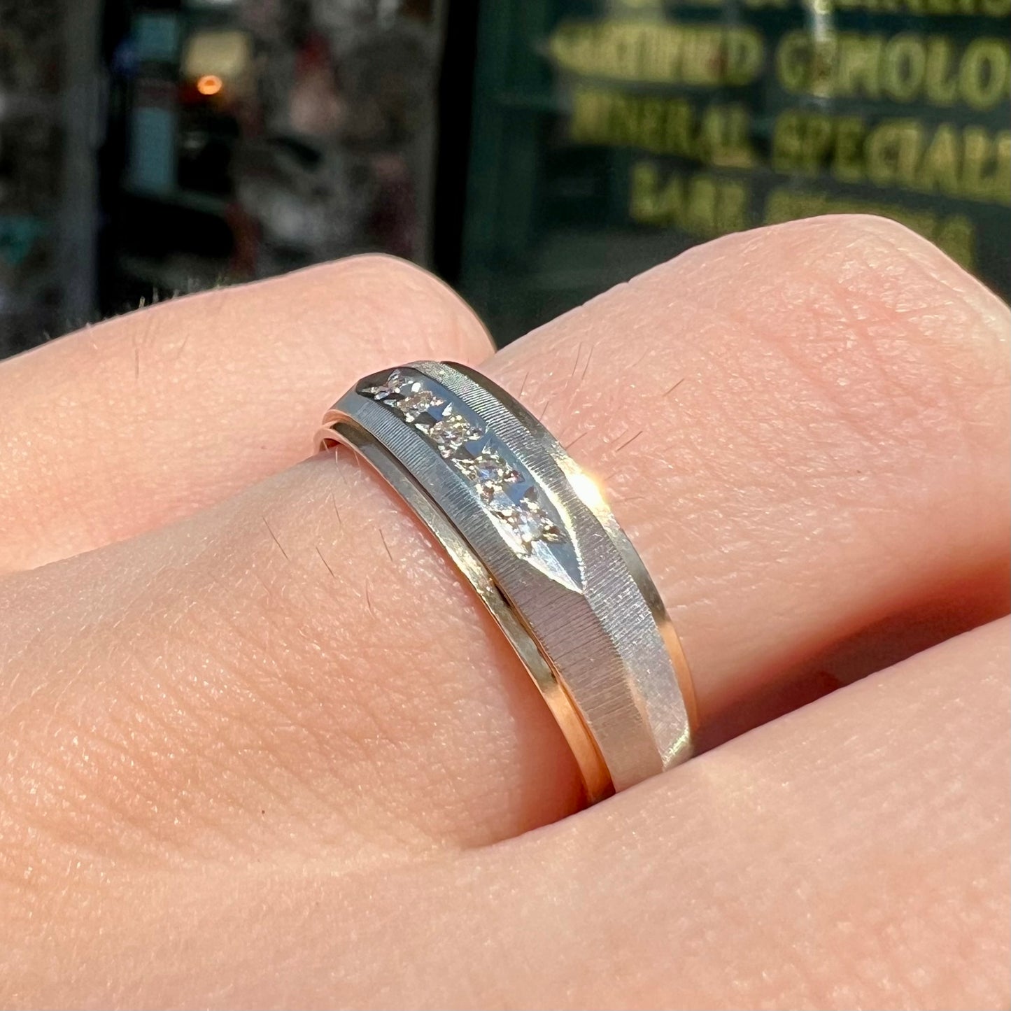 A unisex, two-tone white and yellow gold diamond wedding band. The white gold is textured.