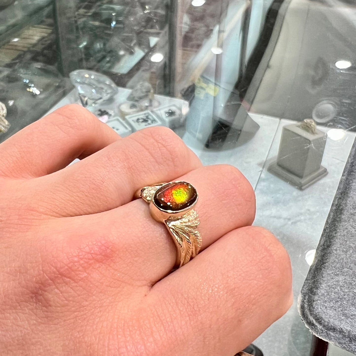 A unisex oval cabochon cut fire agate ring cast in yellow gold. The stone flashes green and red colors.