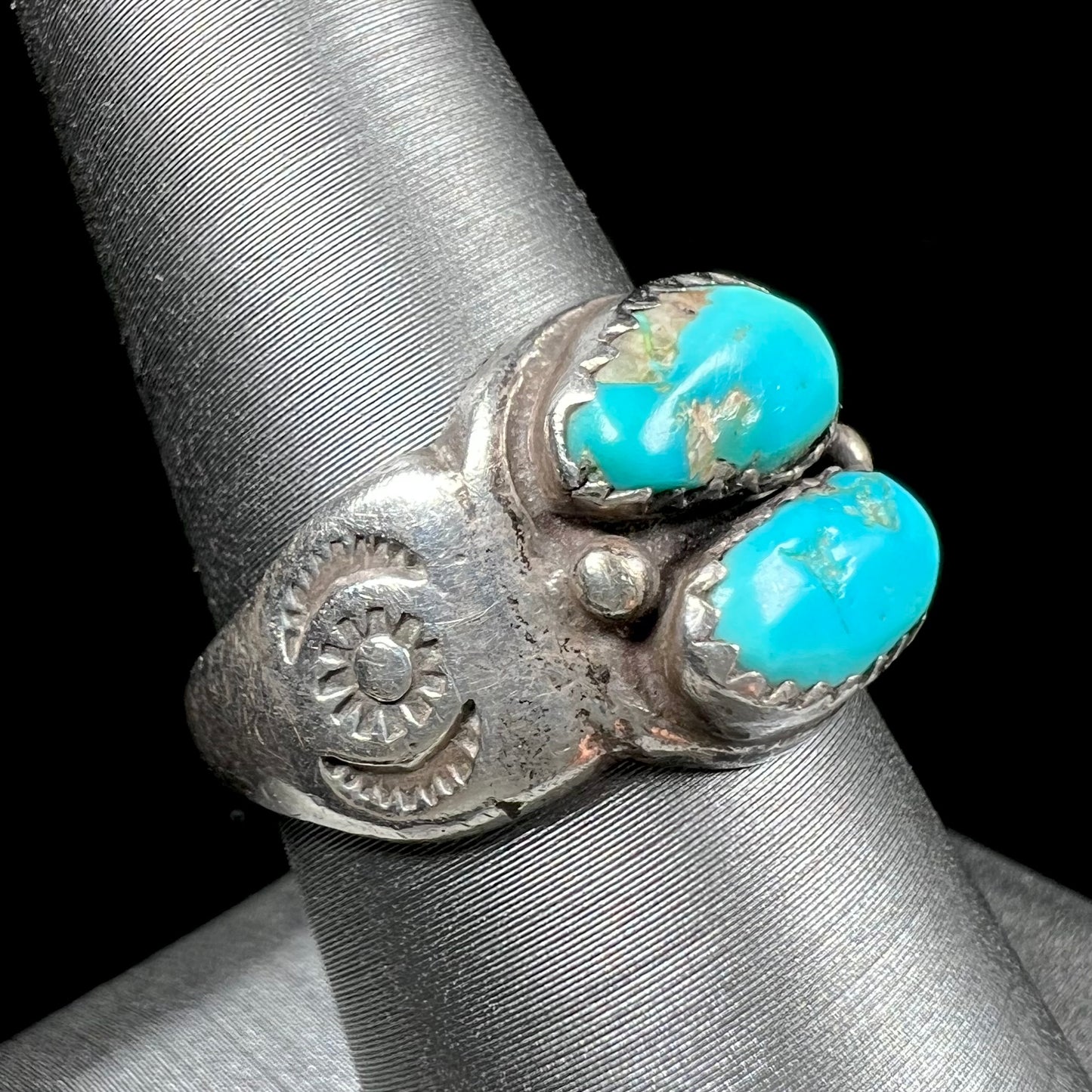 A unisex sterling silver ring bezel set with two Pilot Mountain turquoise stones.  The ring is stamped with sun patterns.