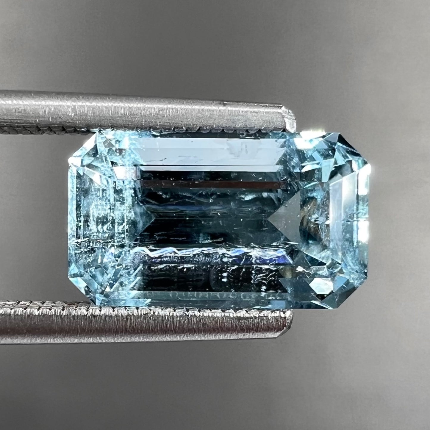 A loose, faceted emerald cut aquamarine stone. The stone is icy blue in color, indicative of Vietnamese origin.