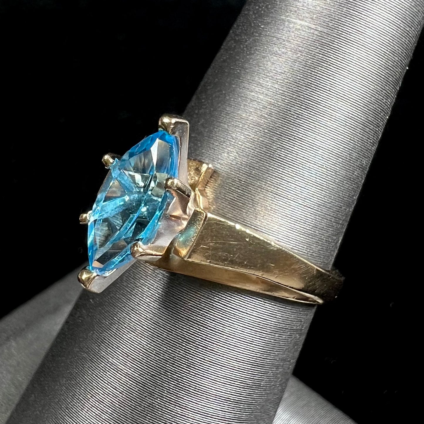 A ladies' estate yellow gold ring, prong set with a marquise cut blue topaz stone. There are scratches on the shank.