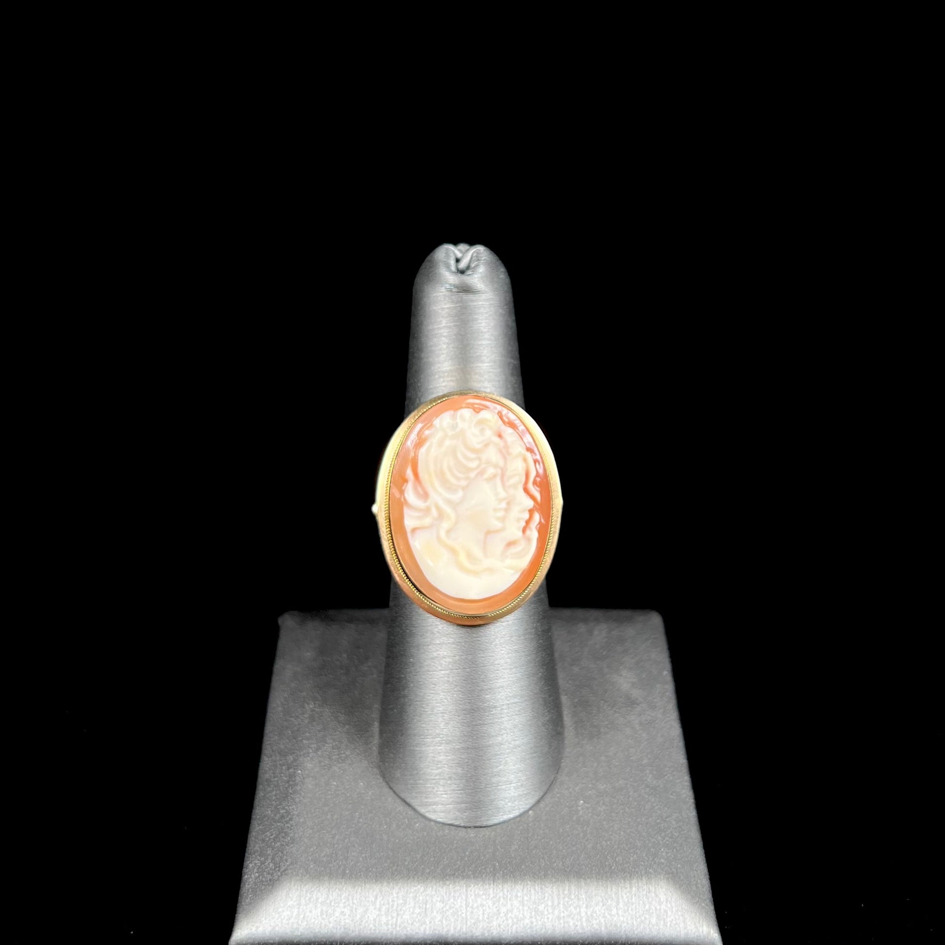 A ladies' vintage cameo solitaire ring in yellow gold.  The cameo is carved from shell and depicts the side profile of two womens' faces.