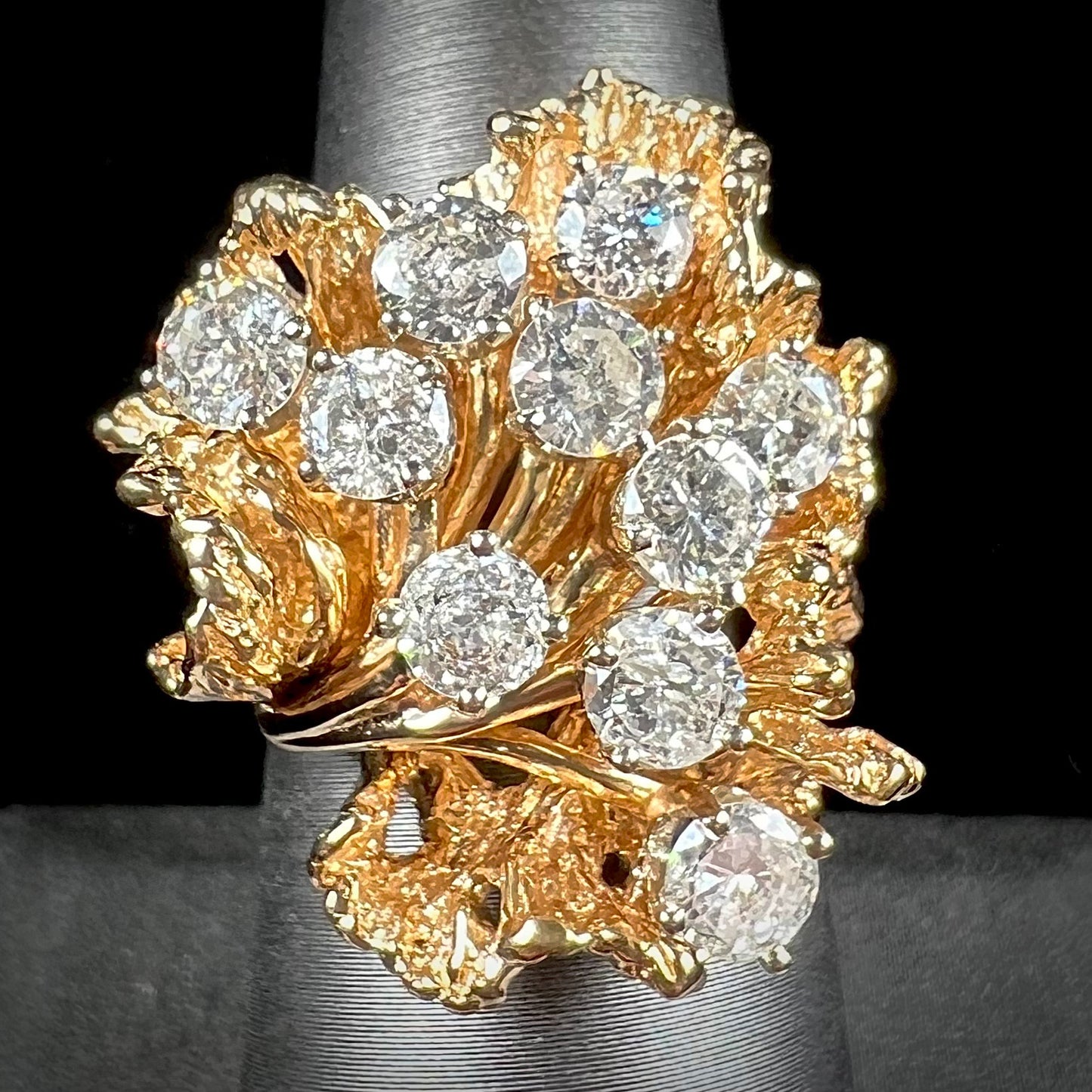 A ladies' 1950's style yellow gold and diamond cluster ring. The ring is shaped like a leaf with 10 round diamonds set in it.