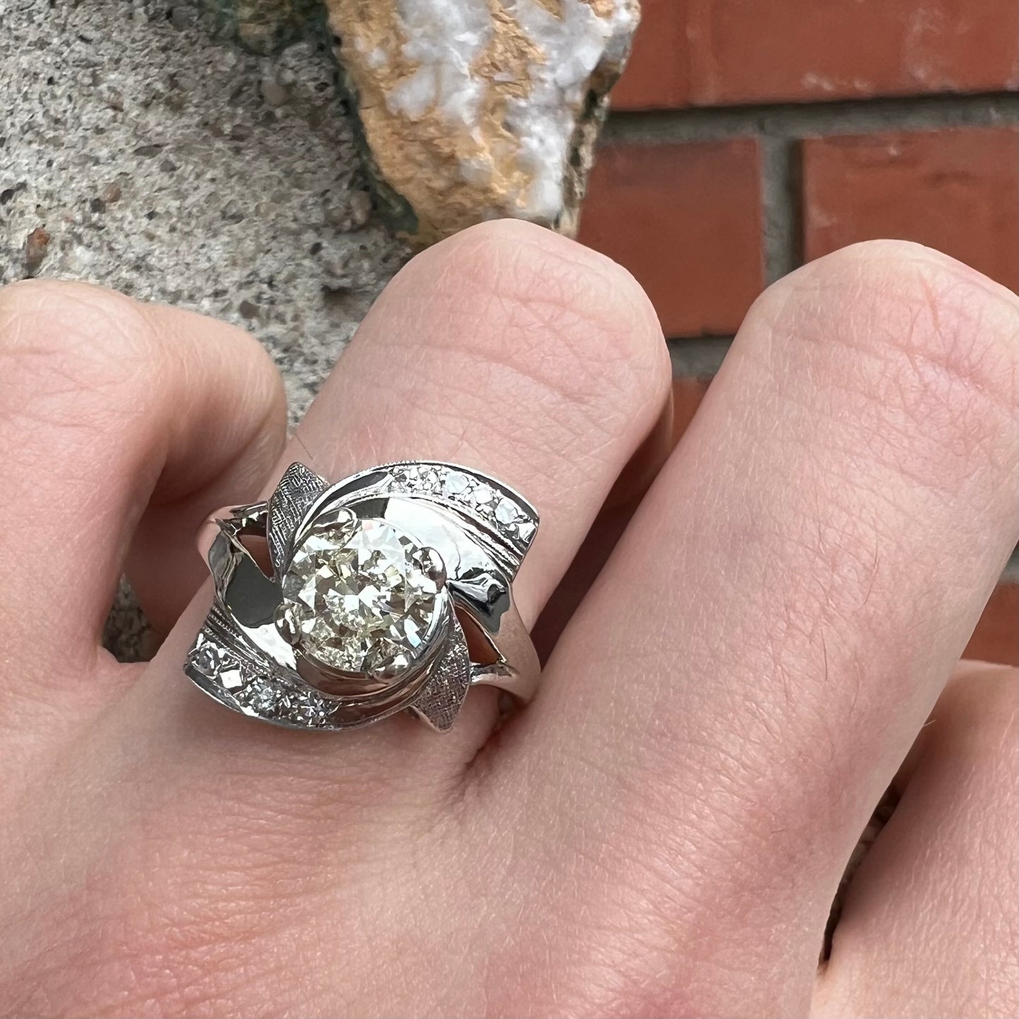 A vintage, Art Nouveau style diamond engagment ring.  The ring is white gold with a yellowish, M colored, 1.24 carat diamond.