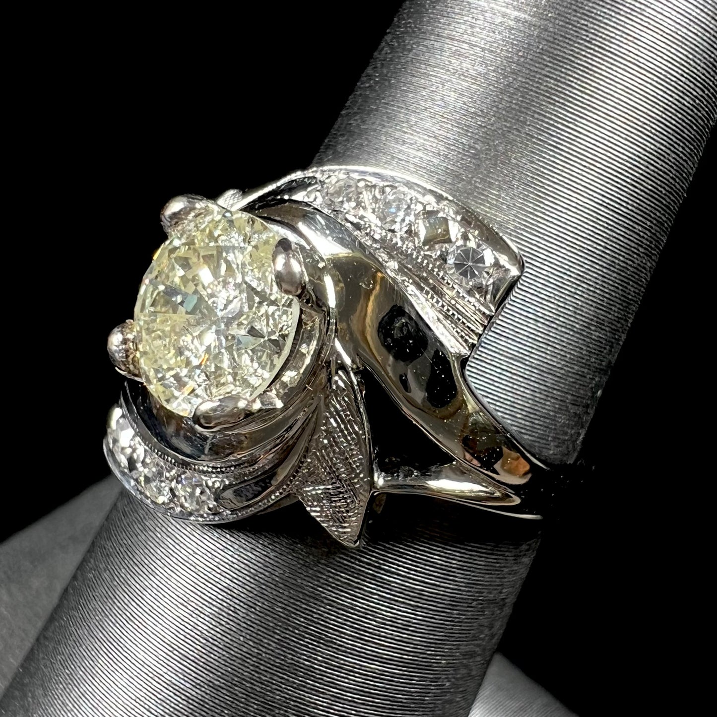 A vintage, Art Nouveau style diamond engagment ring. The ring is white gold with a yellowish, M colored, 1.24 carat diamond.