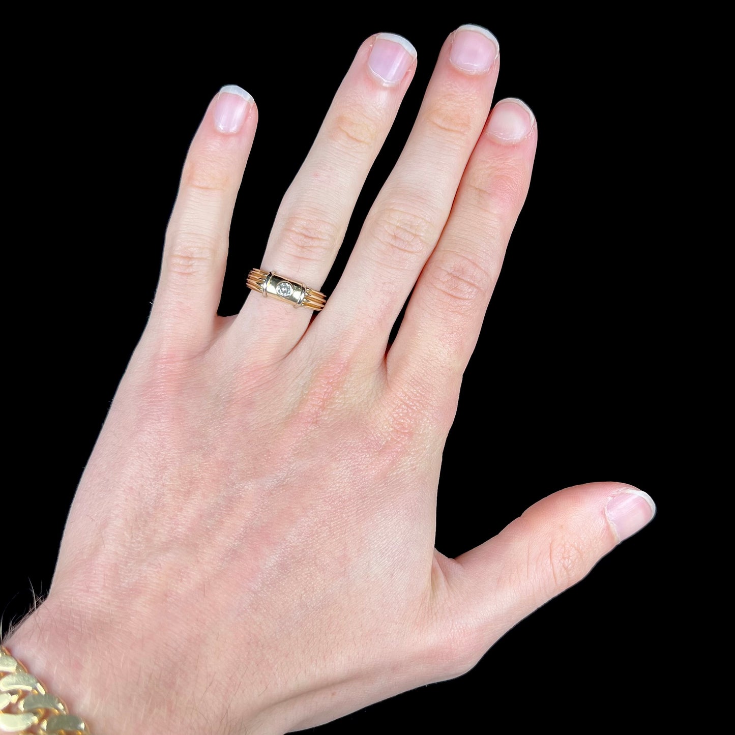 A unisex, vintage style two tone yellow and white gold wedding ring bezel set with a round diamond.