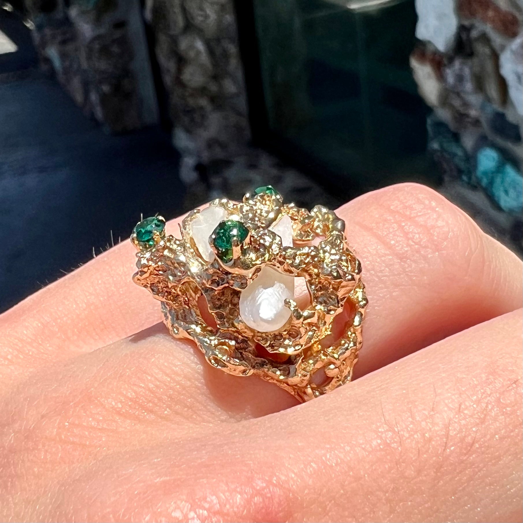 A vintage 1950's gold cluster ring set with freshwater pearls and green imitation emeralds.