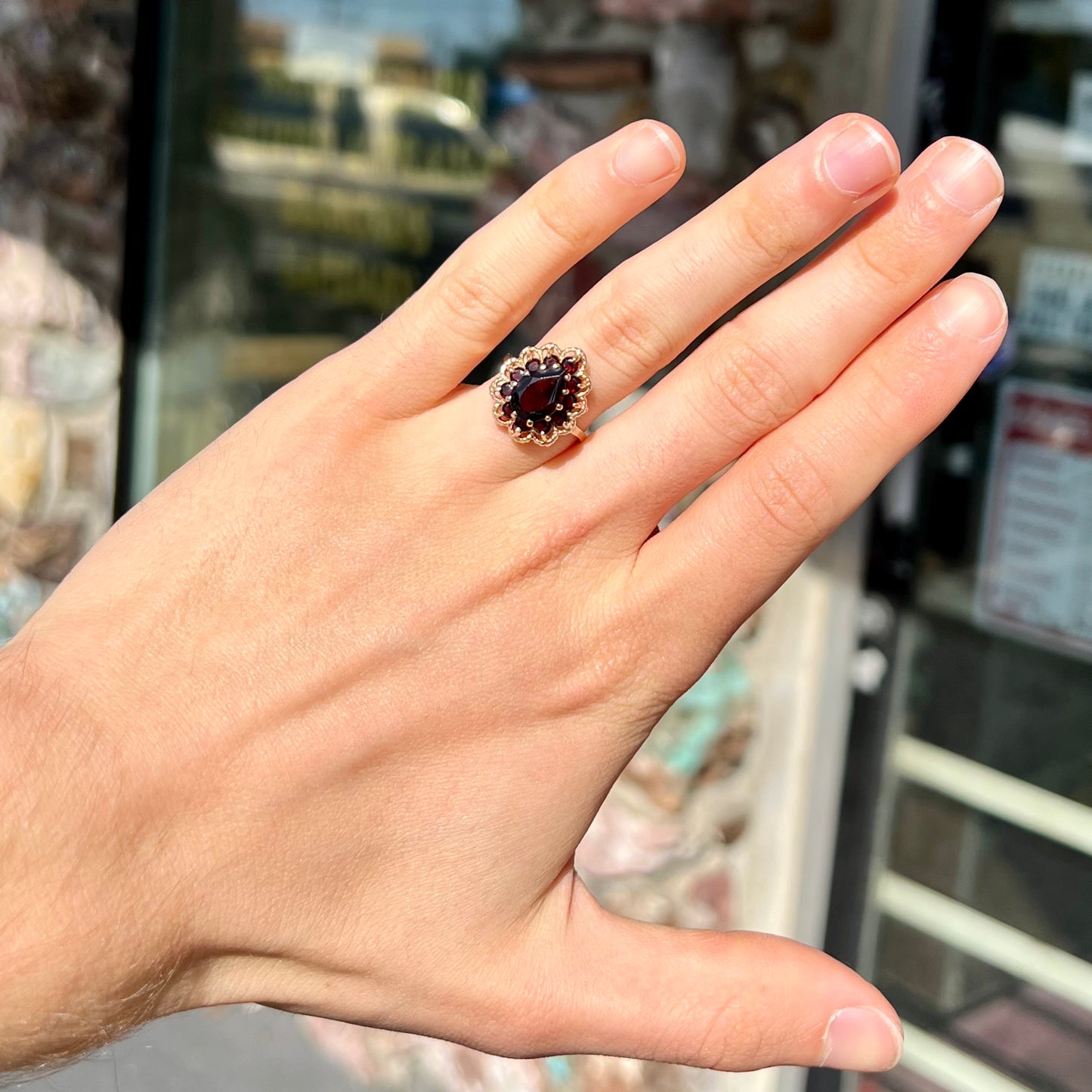 A vintage, 1940's style yellow gold ring set with a pear shaped almandine garnet. A halo of round garnets surround the center stone.