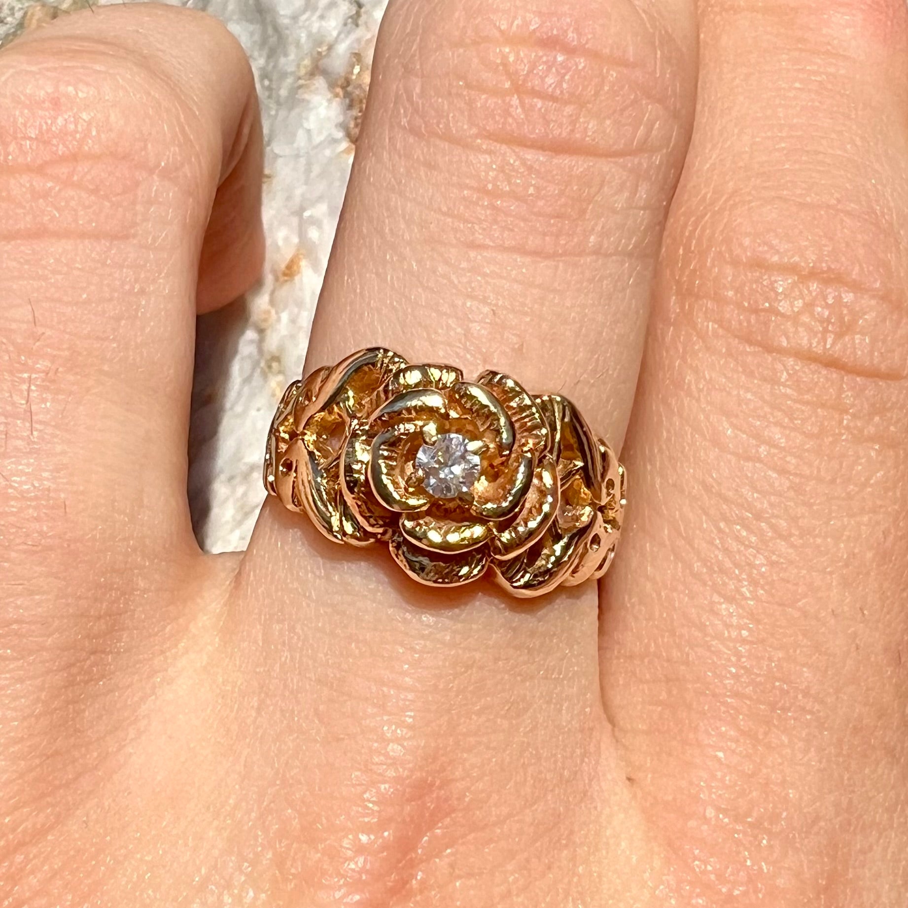 A ladies' yellow gold rose style ring set with a natural 0.10ct diamond.