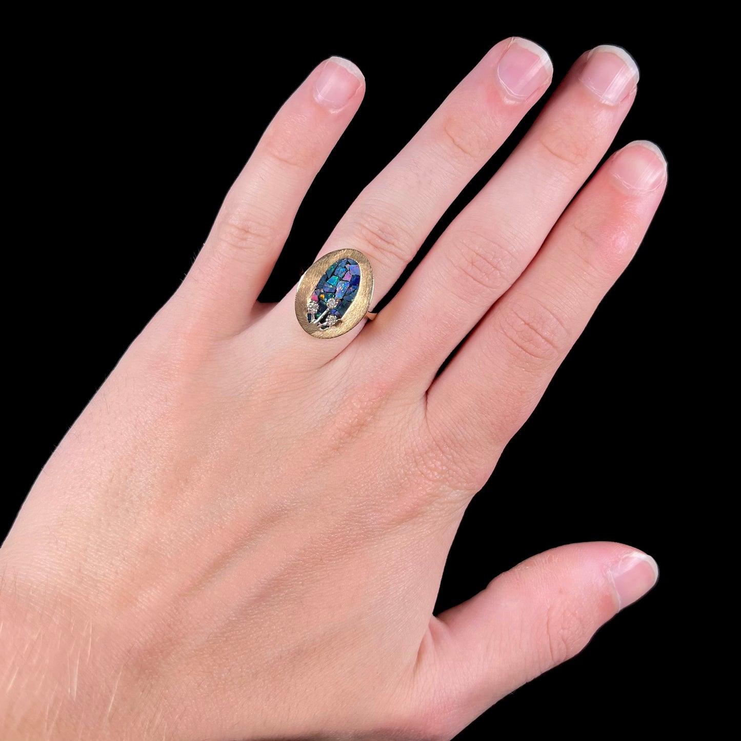 A vintage mosaic opal ring set with diamond accents in 10 karat yellow and white gold.